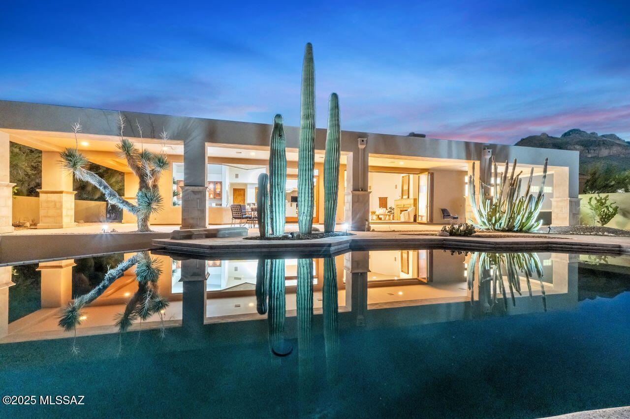 Discover refined desert living in one of Tucson's most prestigious gated communities—Pima Canyon Estates. Nestled on a private one-acre homesite with breathtaking Catalina Mountain views, this 3,316 sq. ft. residence embodies sophistication, serenity, and the true spirit of the Tucson lifestyle. Every detail of this home reflects timeless craftsmanship, from the rich mesquite wood flooring and custom hickory cabinetry to the 8-foot alder interior doors that elevate the home's warm, organic aesthetic. The north-south orientation fills each room with soft natural light while maximizing mountain and desert views. Designed for both intimate living and effortless entertaining, the spacious great room flows seamlessly to the outdoors, where a PebbleTec pool and spa create a private resort oasi Gather around the poolside fireplace with guest seating, framed by lush desert landscaping and mountain silhouettes that define Tucson's desert luxury. With three bedrooms and four baths, this home offers versatility and privacy for family and guests alike. The chef's kitchen, open-concept living areas, and expansive outdoor spaces make this residence ideal for year-round enjoymentwhether you're watching the sunset from the patio or hosting a dinner under the stars. Located just minutes from La Encantada's premier shopping and dining, world-class golf, hiking trails, and top-rated schools, this Pima Canyon gem is more than a homeit's an invitation to experience the beauty and ease of Tucson luxury living.