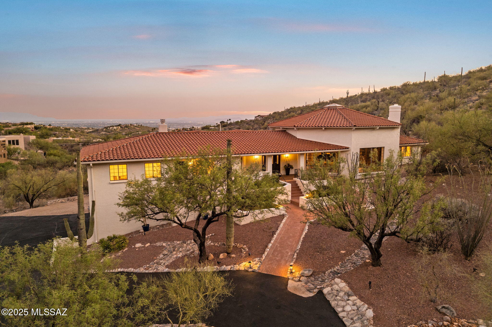Welcome to Villa Puesta del Sol, a timeless residence of understated elegance nestled in the prestigious, guard-gated community of Finisterra on a private 2+acre view lot. Designed and built by renowned Tucson builder Mike Wachs, this exceptional home blends classic craftsmanship with luxurious modern upgrades, breathtaking city & Catalina Mountain views and embodies the sought-after Catalina Foothills Lifestyle. As you approach, the long private tree lined driveway will lead you to the front entry, beautifully landscaped with the Catalina Mountains towering above and at your fingertips. Enter through the hand carved front door to a grand living room that was designed for entertaining and definitely has a ''Wow'' factor. Walls of custom bookcases frame the beautiful wood burning fireplace A wood clad 20' high ceiling adds warmth to the enormous room while a large picture window brings nature in. A custom walk-up wine bar on the other side of the living room is guaranteed to make holidays and special occasions with family so much more enjoyable. At the heart of the home is a spectacular $200,000+ custom kitchen curated by Dorado Designs, Tucson's premier kitchen design firm. Outfitted with top-of-the-line commercial grade Wolf, Viking, and Sub-Zero appliances, this culinary space balances form and function with abundant integrated storage, refined finishes, and commanding city views from the kitchen sink. The adjacent formal and casual dining areas overlook the dramatic city skyline and backyard.  The luxurious primary bedroom suite is larger than some starter homes and features an enormous walk-in closet big enough to share with your partner or spouse, a spa like bathroom w/steam shower & Jacuzzi tub, double vanities, a private rear patio with impressive city views, and an adjacent home office with private entrance. The split bedroom floorplan is ideal with three en-suite bedrooms all with new carpet & updated bathrooms, a large powder room & a bonus rec room at the end of the hall with pocket doors to hide toys from sight or block the sound of little angels fighting. Downstairs, you will find a car enthusiast dream garage large enough for 4 -6 cars or a small RV or boat. Also downstairs, is a climate-controlled flex space, ideal for a wine cellar, workshop, storage, recording studio or gym. The backyard is a blank canvas, ready to accommodate a pool, sport court, gardens, or outdoor entertaining spaces tailored to your lifestyle. This solid masonry home has been meticulously maintained and thoughtfully updated recently with a new tile roof (2024), 2 new heat pumps, fresh interior and exterior paint (2025), new carpeting (2025), and a newly paved driveway (2025). Don't miss this rare opportunity to own one of Finisterra's finest properties, where luxury, location, and lifestyle converge. Residents of Finisterra enjoy exclusive access to community amenities including a heated Olympic lap pool, tennis and pickleball courts, clubhouse for private events, and 24/7 guarded gate access. Ventana Canyon Country Club & Lowes Ventana Canyon Resort are a short 5 min drive away and offer golf, tennis, social & spa memberships.