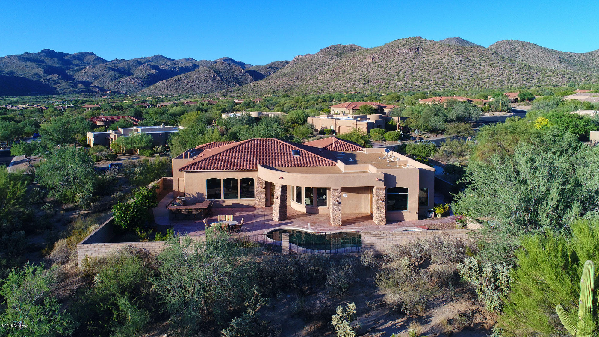 Welcome to gracious, relaxed and private resort like living in this perfectly situated and highly upgraded home in gated Dos Lagos at Dove Mountain in the desirable northwest quadrant of the Tucson Metroplex. The Dove Mountain area includes multiple golf courses, the Gallery Club with golf, private restaurants and pool, the Ritz Carlton with great restaurants, bar and spa services, hiking and bike paths and easy access to groceries, shopping, medical and other services, and quick access to I-10 for airport and Phoenix. There is also a private FBO nearby for Net-Jetters. The home is lovely and elegant, with golf course and/or mountain views from most of the windows...and windows there are in this naturally well-lit environment. Entry is through a courtyard with mature sego palms and through distinctive double doors into the large foyer. The spacious dining room on the left enjoys views of the courtyard and mountains beyond, as does the sitting room/office on the right. Onward into the greatroom, with its bank of tall windows providing views over the resort-style back yard and beyond to the peaceful green of the golf course and mountains in the distance. Relax besides the tall beehive fireplace (gas log) on chilly evenings. The kitchen is a WOW, with NEW GE stainless appliances, a long breakfast bar for chats with the cook, lots of cabinets and handsome granite counters, a five burner gas cooktop on the island and a walk-in pantry. Adjacent is the breakfast area with a curved wall of windows providing views of the pool/spa, golf course and mountains in the distance. Step outside and enjoy the quiet, no sounds except the birds to greet you....such a rarity in life now! The flag-stone-like terrace (with radiant heat for chilly winter evenings!) provides lots of room for gathering, entertaining or just putting up your feet and relaxing as you enjoy the open views of the sunset, with surround-sound music as desired. The rear of the home is home is east-facing, an excellent orientation for this area, and our sunrises can be spectacular. The heated free=form pool and adjacent spa provide a gentle water feature. Mature vegetation includes citrus trees. Back inside, the North Wing of the home is entered through a circular vestibule leading to the master suite, with an oversized bedroom enjoying more delightful views and double glass doors to the outdoors. The TWO huge walk-in closets would be reason alone for some fashionistas to fall in love with this home, ask the listing agents for photos of how these areas could be transformed into magical spaces! The bath area is comfortable, with two sink areas topped with granite, a large oval tub and generous shower with a glass block wall and controls for the water BEFORE one enters the shower---smart arrangement! This wing also includes another bedroom and bath, a large laundry room with cabinets and utility sink, and a three car garage. The South Wing of this lovely home includes two additional bedrooms, each with views and its' own bath, and a substantial sitting room that could easily be home to a large screen TV and become the "media room". As for the neighborhood, the owners report that it's a friendly one, with caring neighbors and an occasional block party. The homeowners have a lot of pride of ownership and keep the Dos Lagos area clean and in good repair. There is plenty of room for family including adult children and grandchildren to visit, yet the home is equally comfortable for two people, with workspace for hobbies and office space as well. Multiple upgrades are detailed in the ....... and include a lot premium of $140,000, builder upgrades of nearly $24,000 and sound system addition of $7000. Well built by Sterling Homes, a respected Tucson homebuilder, this is a forever home and we look forward to showing it to you.