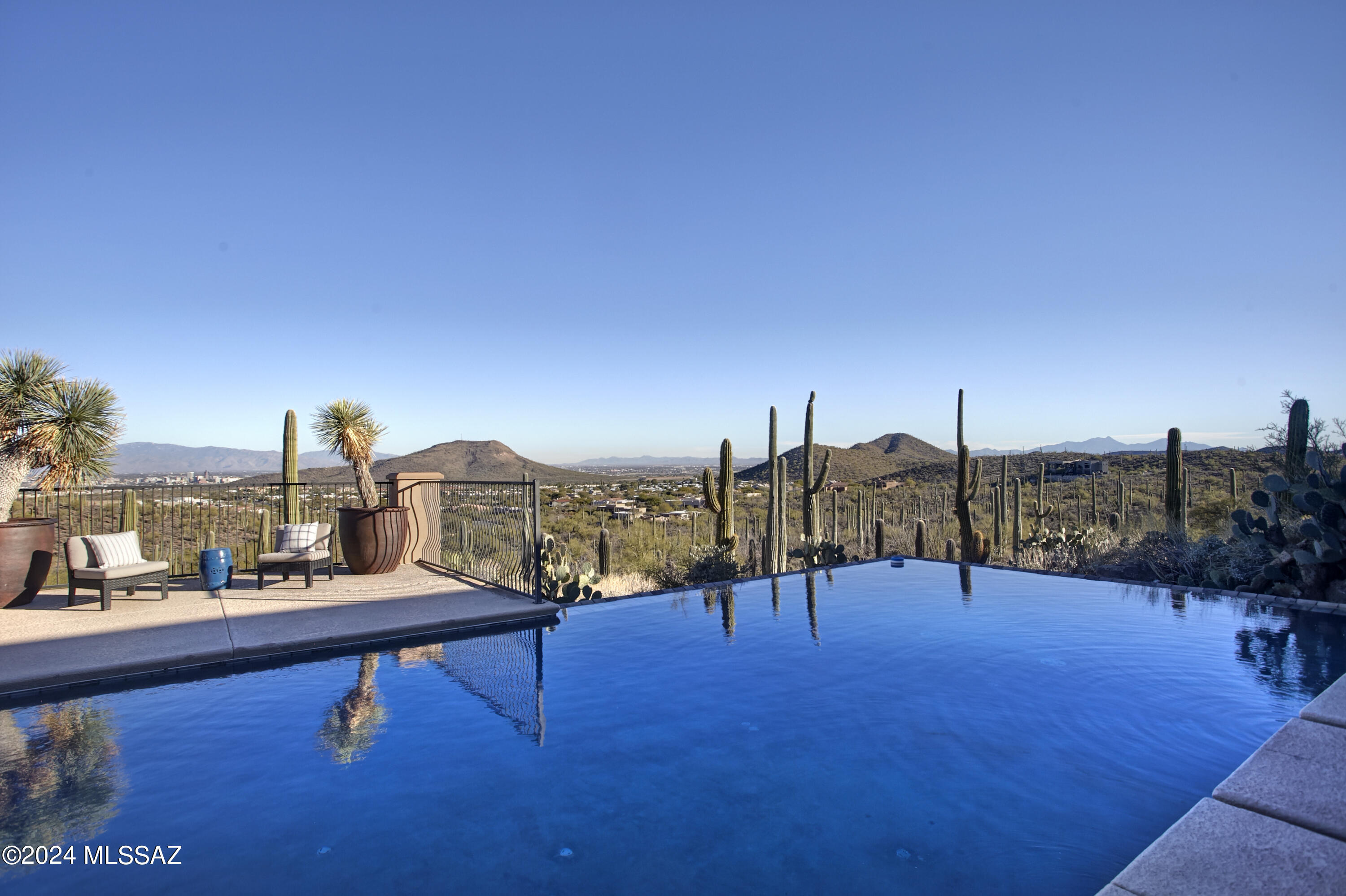 A desert oasis near Downtown Tucson, AZ. Sitting high on a 3.3-acre lot with incredible views of the desert, mountains, and city lights, 380 N Resort Hills Place awaits. With only a few other luxury homes in this small, gated enclave, the setting is incredibly private, while the city and lifestyle amenities are easily accessible. Being sold by the original owner, this property was built to the highest standards.  Both the indoor and outdoor spaces were thoughtfully crafted and positioned to maximize the residential experience. The 4,977 square foot home showcases timeless beauty and elegance. Stone floors, custom millwork, solid doors, expansive glass, and iron blanket the space. Allowing for a variety of layout possibilities, the home includes 5 bedrooms, 5 full bathrooms (including a pool bath), an office, gym and 2 half bathrooms. Windows were carefully placed to maximize views from every room. Naturally set up for entertainment, the kitchen and living spaces flow seamlessly to an expansive covered patio, allowing for large gatherings.

Outdoors, the Tucson lifestyle is truly showcased. Wrapped by a saguaro studded hillside with layers of landscape, there is a deep connection with the desert. A variety of zones, either poolside or along the terrace, create natural spaces for lounging, dining, or entertainment. Tucked away, an area with synthetic grass creates the perfect place for yoga or pets.

The extended 3 car includes a workshop area, an AV room and storage closets.

This location offers quick access to a variety of conveniences and would also work well for commuting or regular air travel.  Immediately available are multiple trailheads with access to the magnificent Tucson Mountain Park for hiking, mountain biking and trail running. The Starr Pass Resort provides 3 golf courses designed by Arnold Palmer, Phil Mickelson, and Nancy Lopez, along with fitness facilities, a full-service spa and dining. Downtown Tucson is a short drive, offering residents city life with robust restaurant offerings, unique shops, cultural events, and festivals.