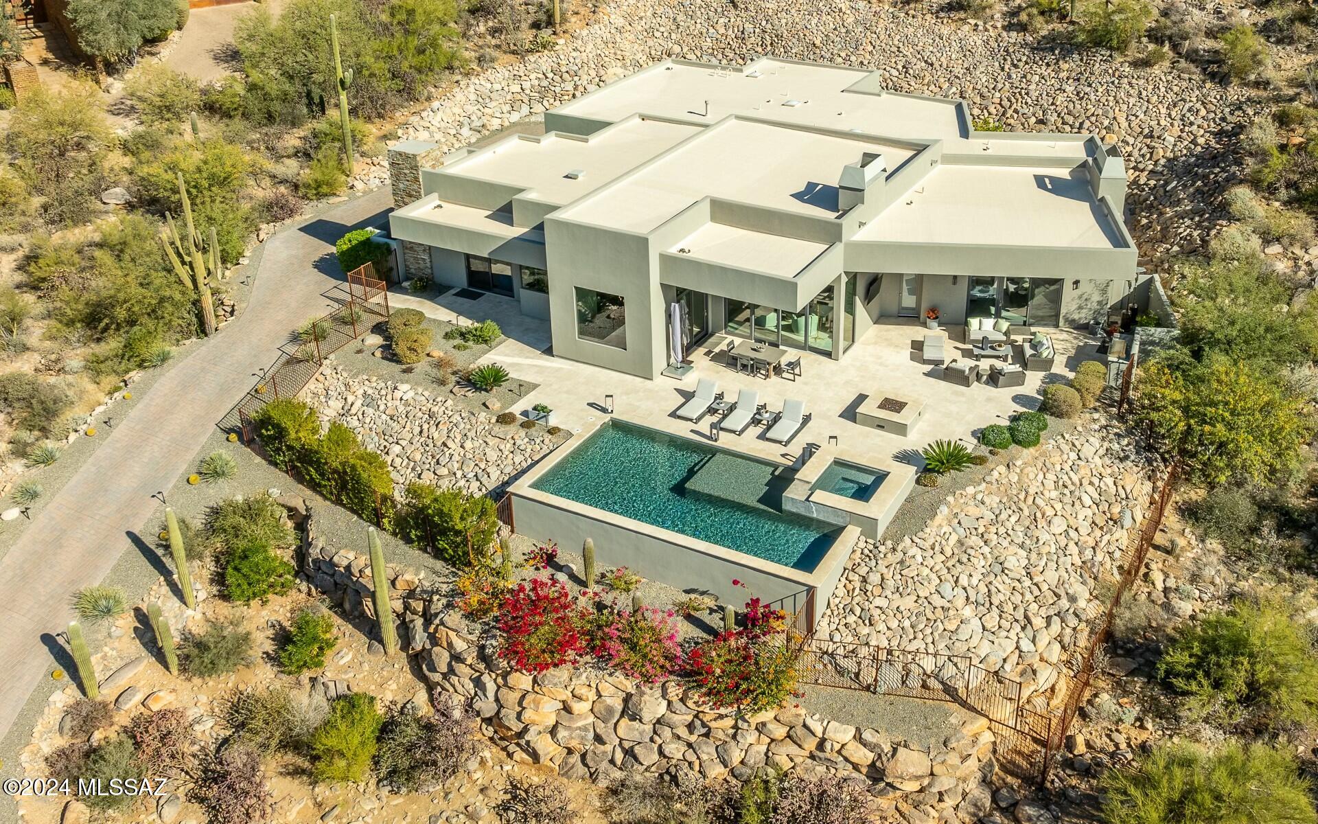Mesmerizing views from this almost still-brand-new, barely lived in, luxury contemporary. Overlooking the 5th green of the Gallery North course you will enjoy unparalleled viewings from your hillside home, Great room concept home - open and spacious w/gourmet entertainers kitchen and separate custom wet bar area. 15ft ceilings allow panoramic views from basically every room in the home. 10ft retractable sliding doors open up to a spacious and entertaining backyard w/BBQ station, large fire pit, pool & spa. Easy flow indoor-outdoor living.  Guest bedrooms 1 & 2 enjoy a private rear patio nested into the hillside of saguaros w/citrus planters that produce wonderful fruit. Two floor to ceiling stacked stone fireplaces (great room and primary bedroom). A stunning barely lived in home!