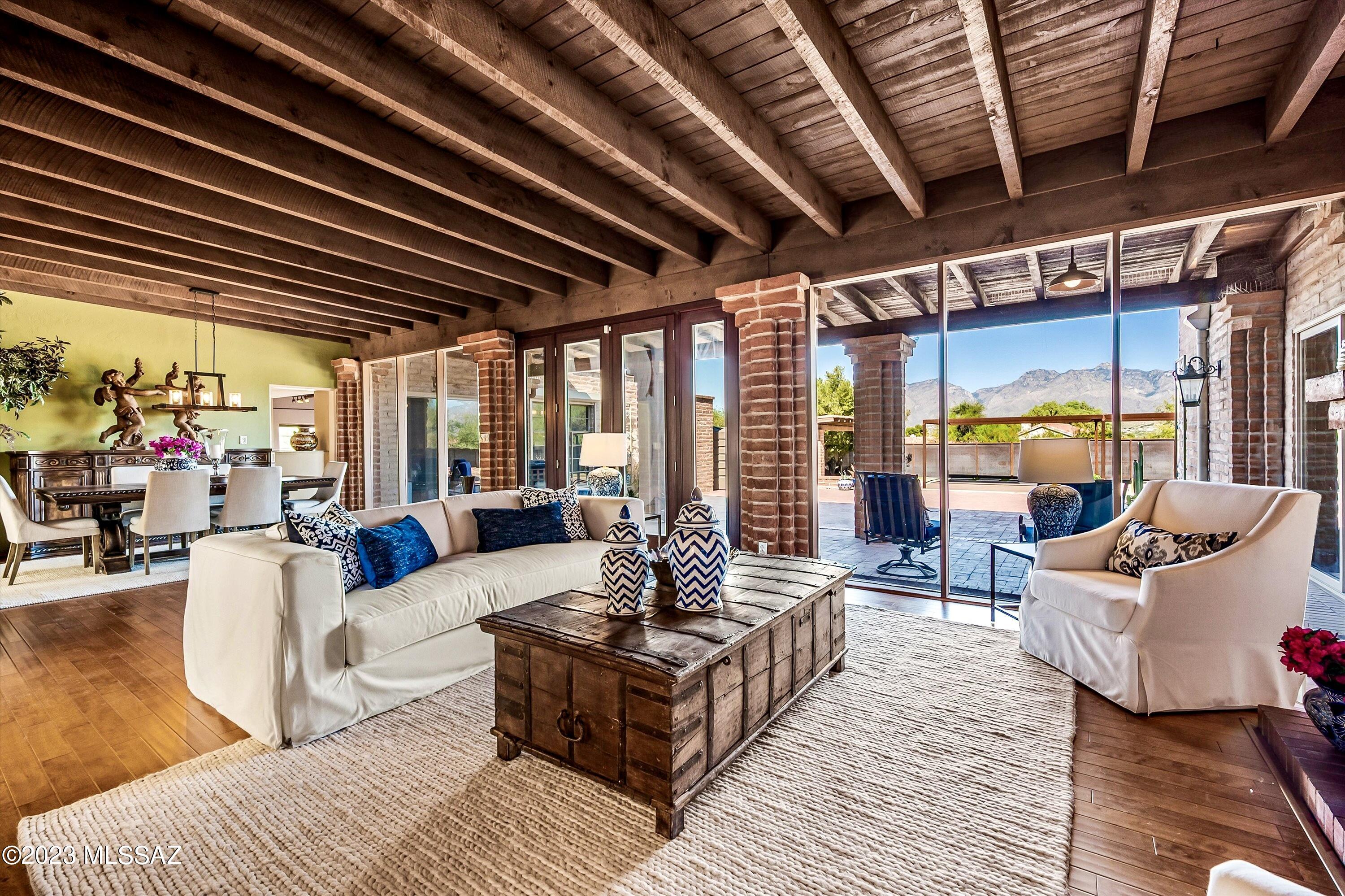 This distinguished property is an architectural gem within Tucson's city limits. Spanning across 2.46 acres on three R-1 lots, it seamlessly integrates a convenient location with privacy and opportunity for future expansion with no HOA. Classic Territorial home designed by the famed architect Lewis Hall, offers timeless Spanish inspired features; Burnt adobe brick exterior and interior, floor to ceiling windows, three fireplaces, rough sawn wood ceilings and exposed beams throughout from the Mt Lemmon saw mill, and ocotillo branch covered courtyard and entryway. Each window and outdoor living space frames breathtaking panoramic mountain or desert views, granting a constant connection to nature. The views from the majestic master suite & guest quarters create a true sanctuary. The attached level guest quarters are ideal for visitors, generational living, office, or studio work having a private entrance and patio adjacent to dedicated parking. One could easily incorporate ADA features as desired with the space already having wide doorways and hallways, and a roll-in shower. The sprawling outdoor living areas accommodate relaxation and entertainment alike, having numerous patios, a large ramada with power, sauna, and are accented with custom artisan metal fencing, artistic panels, sunshades, and window awnings. Multiple vehicles, including boats and RV's can easily be accommodated within the expansive driveway. The combined acreage also presents opportunities for additional structure development. Many improvements have been made to this property, ensuring an unparalleled canvas for inspired living including; Updated kitchen and bathrooms, three new zoned HVAC systems with solar assist and whole house air purification, new plumbing service lines and connection to city services, two 865 gallon water harvesting systems, whole house water filtration system, security rolling shutters, new exterior Pella doors, and a fully secured yard for pets. There is still a large swimming pool of approximately 800 sf, that has been covered with composite decking and large sun shades. For those desiring a swimming pool, it could be reclaimed for a minimal investment compared to the cost of constructing a new pool. Please come see this special property!