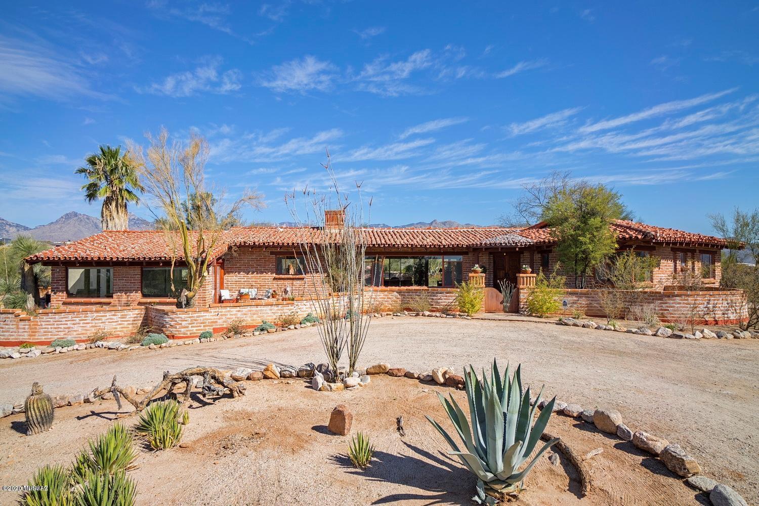 Charming Old Tucson style Hacienda home sits on the ridge with majestic views. Burnt Adobe home was remodeled with a focus on quality and character. Plaster interior walls, exposed decking and beam ceilings. Mexican tile kitchen and baths, hand crafted mesquite bar, concrete floors and tiles are a few special features. Large windows and French doors surround the home affording views of two mountain ranges, and city views from front. A large resort style porch off the back is perfect for entertaining. Various patios can be accessed around the house along with outdoor fireplaces. The pool sits back off the landscaped enclosed backyard with mountain views as well as privacy. No HOA.