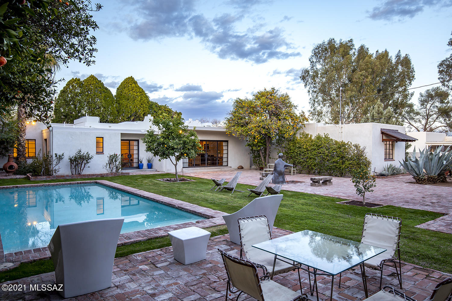 Great design is timeless. This will only be the second time the ownership outside of the original family that the home will have changed hands, providing a rare opportunity to own a piece of Tucson history. The c. 1938 Territorial home feels just as elegant today as it was when it hosted fantastic dinner parties for the Duke and Duchess of Windsor while they enjoyed a winter escape in the Sonoran Desert staying steps away at the Arizona Inn. Marks of great craftsmanship are evident throughout the home. Hand troweled, smooth stucco exterior walls encase period elements like the old-growth white oak hardwood floors, handcrafted steel glass doors opening out to the backyard, and a simple, modern, contemporary studio. With its polished concrete floors and interior walls constructed of exposed brick and plate steel, the studio is perfect as a home office, art studio, or guest suite. The four-bedroom main house offers a split bedroom floor plan and four vintage tiled bathrooms. The sophisticated living room is rich with texture from grasscloth wallpaper, beamed ceilings, and one of three wood-burning fireplaces. The home also has a large open finished basement with high ceilings and window wells letting in natural light, a wine cellar and additional storage. The backyard is an escape to your own oasis with a sparkling pool, lush green lawns, large bricked patios and gabled tree house all tucked away behind large, mature foliage and old grove citrus trees. Full of classic Tucson charm and character, this property is a contributing home to the Blenman Elm neighborhood National Historic District. All within walking distance to Banner Hospital and the University of Arizona.
