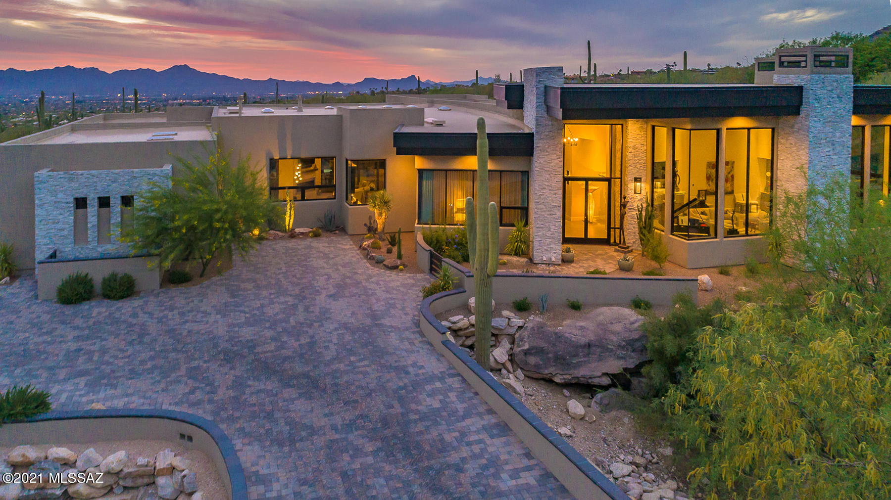 Stunning contemporary in Tucson's most exclusive community- The Canyons. Tucked away high in the Foothills enjoy jaw dropping city lights and beautiful mountain views. This 5bed/4bath masterpiece sits on over an acre w/ 5,187 sq. ft. and guest house w/ kitchen/living room at 580 sq. ft. Features throughout include Pella doors/windows, oversized porcelain tile floors, oversized alder doors throughout, expansive walls of windows, & master suite w/ w/i cedar closet; spa bath; & outdoor shower. Chef's kitchen includes large quartz island, granite counters,  and state of the art appliances. Kitchen leads into breakfast area & family room w/ outdoor access through oversized sliding doors. Back yard is a true retreat w/ pool/spa showcasing the amazing views, full outdoor kitchen, & fire pit.