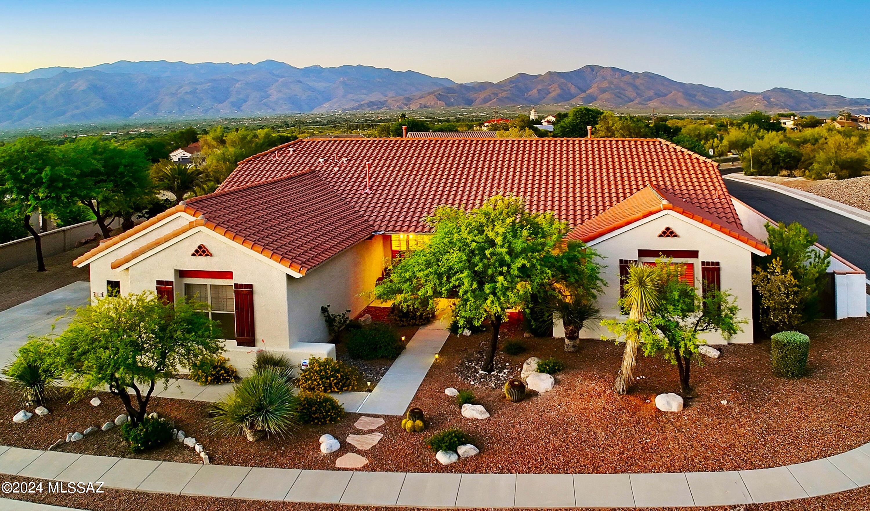 Welcome to a perfect blend of elegance and comfort complimented with a backyard oasis all set on a raised lot providing fantastic sunset and mountain views.  Beautiful double door entry welcomes you into the living and dining areas, perfect for gatherings.  The heart of the home is the generous island kitchen w/granite counters that seamlessly connect to the cozy greatroom w/fireplace. Outdoor living is a delight w/sparkling pool & spa, large covered patio and lovely landscaping with seperate turfed area. Spacious primary is a true retreat, w/2-way fireplace, jetted  tub, sep shower, dual sinks & huge walk-in closet. Plantation shutters add sophistication & privacy. Prime location near Saguaro National Park East.  This home offers not just a place to live, but a lifestyle to cherish