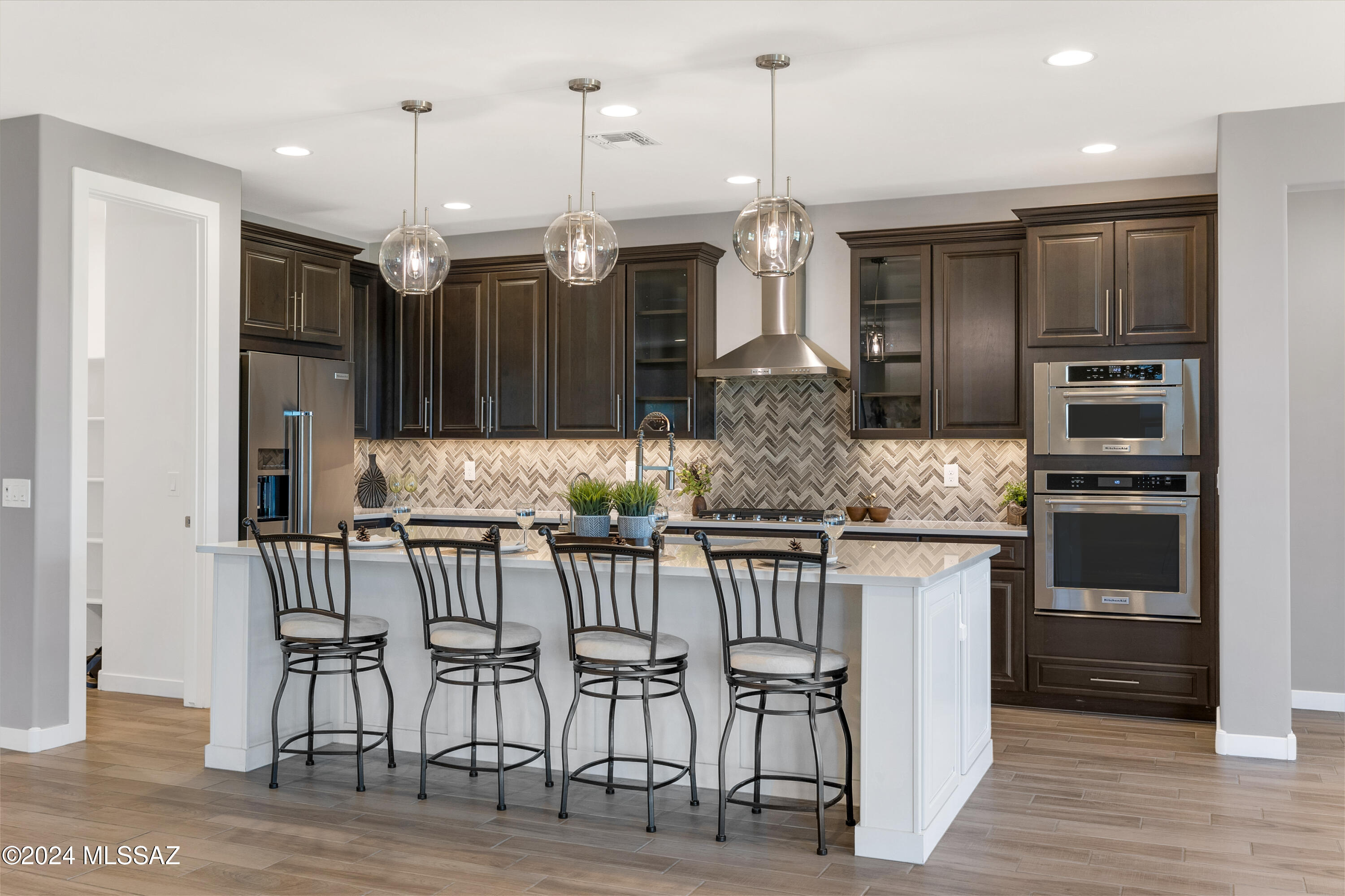 Beautiful View lot in coveted, gated Villages at Silverhawke in Oro Valley.  2020 built Meritage 2342 sqft 3bd/2.5ba Aldea plan with many, many builder + owner upgrades.  No expense spared in choosing the finishes and details of this meticulous home.  Imagine hosting holiday celebrations in the chef's kitchen with two-tone cabinets, 42'' uppers with crown molding, quartz counters, organizational package (pull-outs!), upgraded KitchenAid appliances including gas cooktop, beautiful backsplash and a huge island overlooking the great room. Adjacent to the great room is a pocket office with full cabinets - perfect for homework or hobby space.  Beautiful mountain views from great room and adjacent dining area with sliders to a deep covered porch and fully landscaped north-facing yard with a view fence highlighting the open space behind. Meander the paver pathways in the front yard around to the back where you can enjoy the views of Pusch Ridge from the wood burning firepit or the shade of the porch and trees. Upgraded 16 seer HVAC, neutral wood-look tile floors in the common areas, 8' doors and enhanced can lighting throughout, and convenient up-down shades on the windows! Epoxied 3-car tandem garage with access to back yard.
Owner's suite is an oasis with 'wake-up' mountain views, spa bath with designer tile, a large glass-walled shower and a soaking tub, and an envy-worthy spacious closet fully customized by Closet Concepts. Bedroom 2 has a full length built-in murphy bed with desk and bookcases and bedroom 3 with a walk in closet and a bath between the bedrooms.  Dedicated powder room for guests!  A spacious pantry, huge entry closet, linen closets, full cabinets at the drop zone near the garage and in the separate laundry room, + overhead racks in the garage are just some of the many storage options that are available.
Enhanced electronics packages including holiday lights, surround sound, speakers on the patio and internet. Community offers 3 parks - one is only steps away - and a basketball court and walking trails. Easy access to local shopping, dining, and medical.