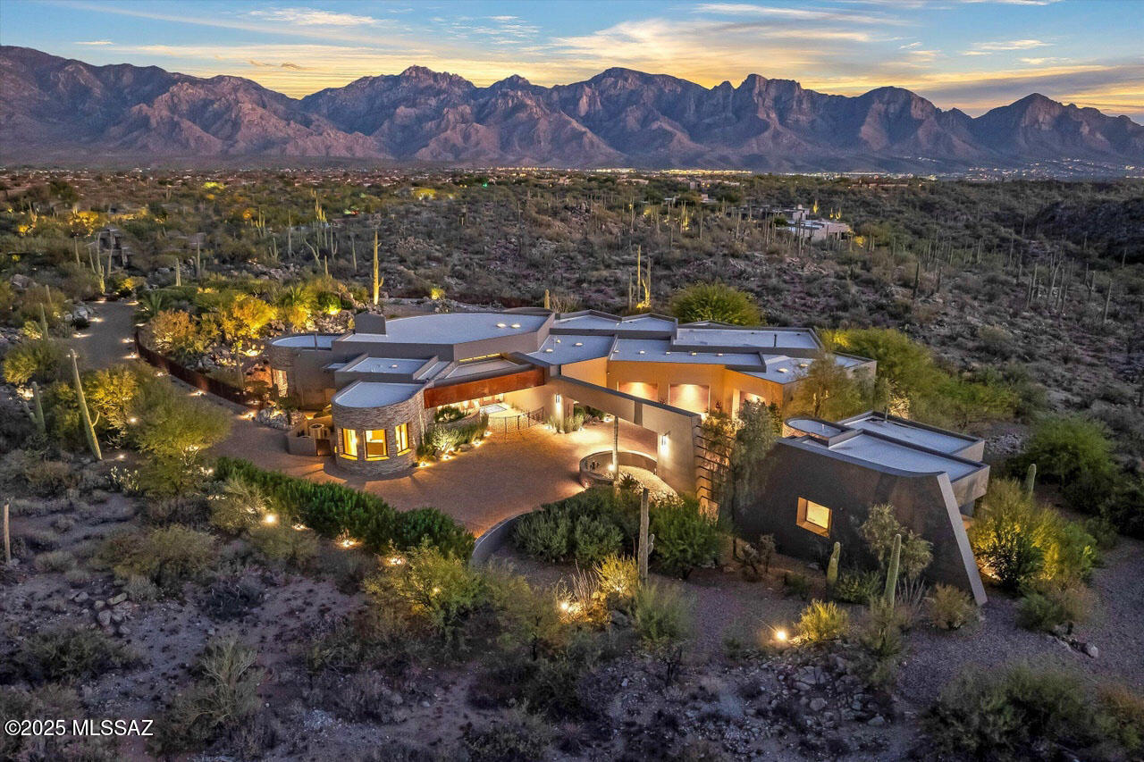 Experience a private architectural masterpiece that seamlessly blends comfort and elegance with the natural beauty of its desert surroundings. Behind a private gated entry, this 5,889 SqFt sanctuary showcases exceptional craftsmanship and breathtaking views of the Catalina Mountains.

The 4,853 SqFt main house highlights a dramatic great room with floor-to-ceiling windows, a striking fireplace, and beautiful architecture, allowing for seamless flow throughout the home. A chef's kitchen with top-tier Thermador appliances is wrapped by a large sit-up bar and provides easy access to the main living, formal dining, and outdoor areas, allowing for easy hosting. The luxurious primary suite offers spa-like amenities, sensational views, and an impressive walk-in closet. It is complemented by additional bedrooms, each with its own different architectural touch and ensuite bath, as well as a versitile den. 

A 1,036 SqFt guest house is connected by a beautifully lit bridge. It offers a private retreat with captivating views, a spacious living area with a fireplace and kitchenette, and a bedroom with an ensuite bath, ensuring a comfortable stay for all who visit.

The expansive yet private backyard is an entertainer's dream, featuring a heated pool and spa with a natural rock waterfall and a grand covered patio with an outdoor kitchen and lounge, providing plenty of seating and dining opportunities. Extended patios offer additional seating options, featuring a fire bowl and a raised patio, perfect for soaking up the sun, cherishing spectacular sunsets, or stargazing under a brilliant night sky.

The exceptionally spacious three-car garage is a standout, offering extended space, custom storage, and additional storage rooms. This home truly caters to those who desire privacy, luxury, scale and functionality in their living space and promises a truly unparalleled lifestyle experience, making it a must-see for anyone seeking the best in indoor-outdoor enjoyment.