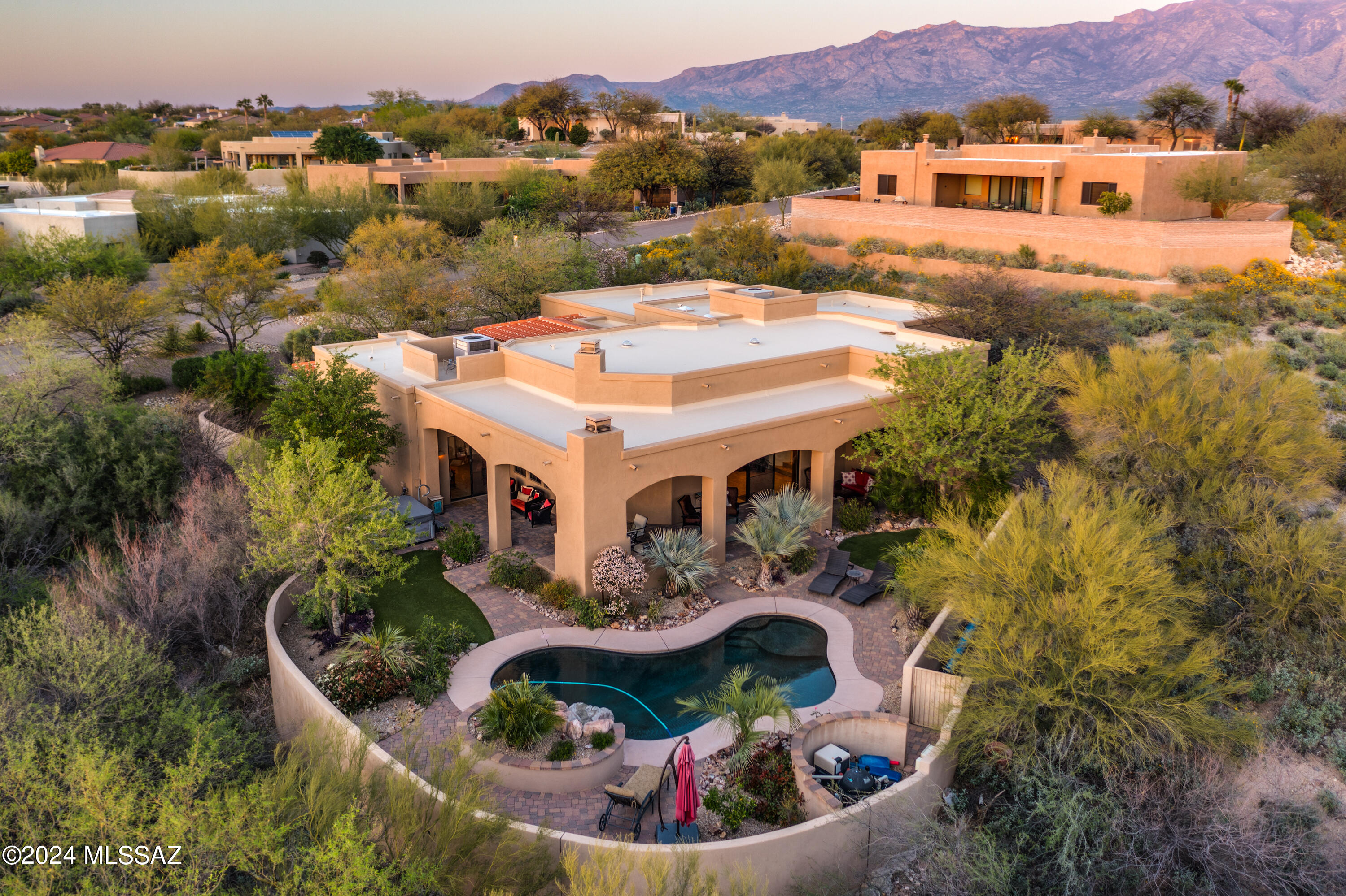 Serene Mediterranean retreat in Oro Valley. Experience private luxury & quiet relaxation in this custom-built split floorplan home of 4 BRs (2 ensuites) & 3.5 baths. Grand entrance into breathtaking Great Room w/ 12' ceilings, stacked stone fireplace & walls of windows overlooking a private backyard paradise. Vacation at home in resort backyard w/ salt water heated pebble tec pool w/ waterfall & professionally landscaped yard of lush tropical plantings. Expansive rear patio for al fresco dining w/ built in gas fireplace and BBQ. Gourmet kitchen w/ Viking appliances, dual ovens, gas stove & granite counters. Formal dining room w/ windows showcasing desert views & resort backyard. Solid Alder 8' doors & cabinets add warmth & luxury. And: 2 50-amp hookups (spa & RV) & extended 3-car garage. The backyard paradise rivals any 5-star resort w/ the romantic lagoon-like pool, fitted with a Pentair system for full remotely controlled automation. Sip a refreshing beverage and lounge peacefully under the shade of breezy palms & flowering plants. High-grade artificial turf and a 50-amp hookup for a future hot tub complete this carefree, visually stunning backyard resort. 

Inside, architectural steps flank the Great Room for easy entertaining with circular flow into the Kitchen and Dining Room and out to the spa-like, tropical paradise backyard. Step down from the Great Room through grand, rustic double doors into a secluded, quiet Primary suite where privacy abounds. Light flows through to a spacious, airy bathroom with garden tub, tiled walk-in shower and dual vanity. 

Directly off the Great Room is the second ensuite (w/ tiled walk-in shower), the perfect space for a quiet library, den, home office or private bedroom! The dramatic and privacy-focused layout of this luxury home continues with two more spacious bedrooms connected by a Jack & Jill bathroom.  A large, open laundry room with extra storage doubles as a mud room for easy loading and unloading of vehicles from the oversized 3-car garage. 

Some furnishings and décor available for purchase.