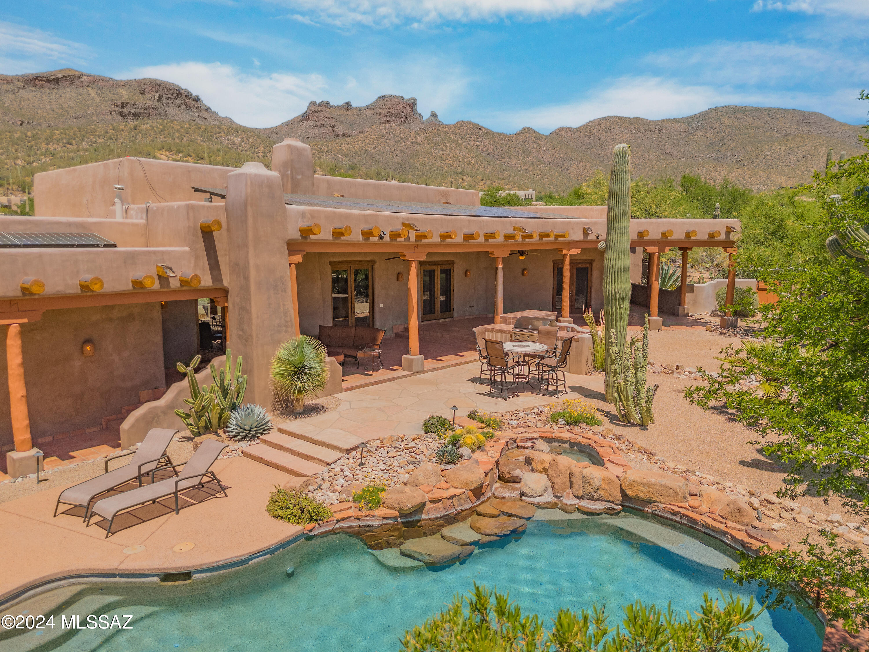 Custom Santa Fe masterpiece by renowned builder, Ray Birch. Boasting opulent craftsmanship: grand viga ceilings, accented w/ skip-peeled, mudded latillas, & saguaro rib-accented doors. Elegantly finished with hand-troweled plaster, 4 kiva fireplaces, Mexican tile, & well appointed art niches. Additional amenities include a beautiful gourmet kitchen, Office/Den, Split Floorplan, 3 car garage w/ A/C & work shop. Large windows & expansive covered patios reveal panoramic mnt views from the 1.4 acre, saguaro-studded lot. Adjacent to a126 acre Pima County Conservation. Indulge in resort-style living amidst the desert landscape, w/ outdoor fireplace, built-in BBQ, sparkling pool w/ natural rock waterfall, spa, & mesmerizing evening sunsets. This is the ultimate in Southwestern luxury living. Welcome to a rare desert gem nestled at the foot of the Catalina Mountains, where luxury meets Southwestern charm. Designed by renowned builder Ray Birch, this custom Santa Fe home epitomizes craftsmanship and elegance at every turn. Step inside this 3 bedroom, three bath, plus Den/office, to discover a masterpiece of architectural ingenuity, where large viga ceilings soar overhead, accented with mudded, skip-peeled latillas, and saguaro rib-accented doors, exuding authentic Southwestern elegance. Hand-troweled imperial plaster walls, four kiva fireplaces, and extensive covered patios enhance the ambiance of warmth and luxury. Indulge in breathtaking panoramic views of the Catalina Mountains from the comfort of your own home. Situated on an oversized lot adorned with majestic saguaros, this property offers a rare opportunity to experience the natural beauty of the Sonoran Desert in all its glory. Meticulously maintained and move-in ready, this turnkey home boasts ample storage and a three-car garage with air conditioning. Escape to your own private oasis in the backyard, where resort-style amenities await. Relax by the outdoor fireplace, entertain guests with the built-in BBQ, or take a refreshing dip in the sparkling pool with a natural rock feature. As evening falls, the beautifully lighted landscape sets the stage for unforgettable gatherings under the starlit desert sky. Immerse yourself in the unparalleled beauty and serenity of desert living in this exceptional Santa Fe retreat. With its stunning design, meticulous maintenance, and resort-style amenities, this home offers a rare opportunity to experience the ultimate in Southwestern luxury living. Tucson's renowned golf, cycling, hiking, and culinary delights beckon, all mere moments from this exquisite desert sanctuary.