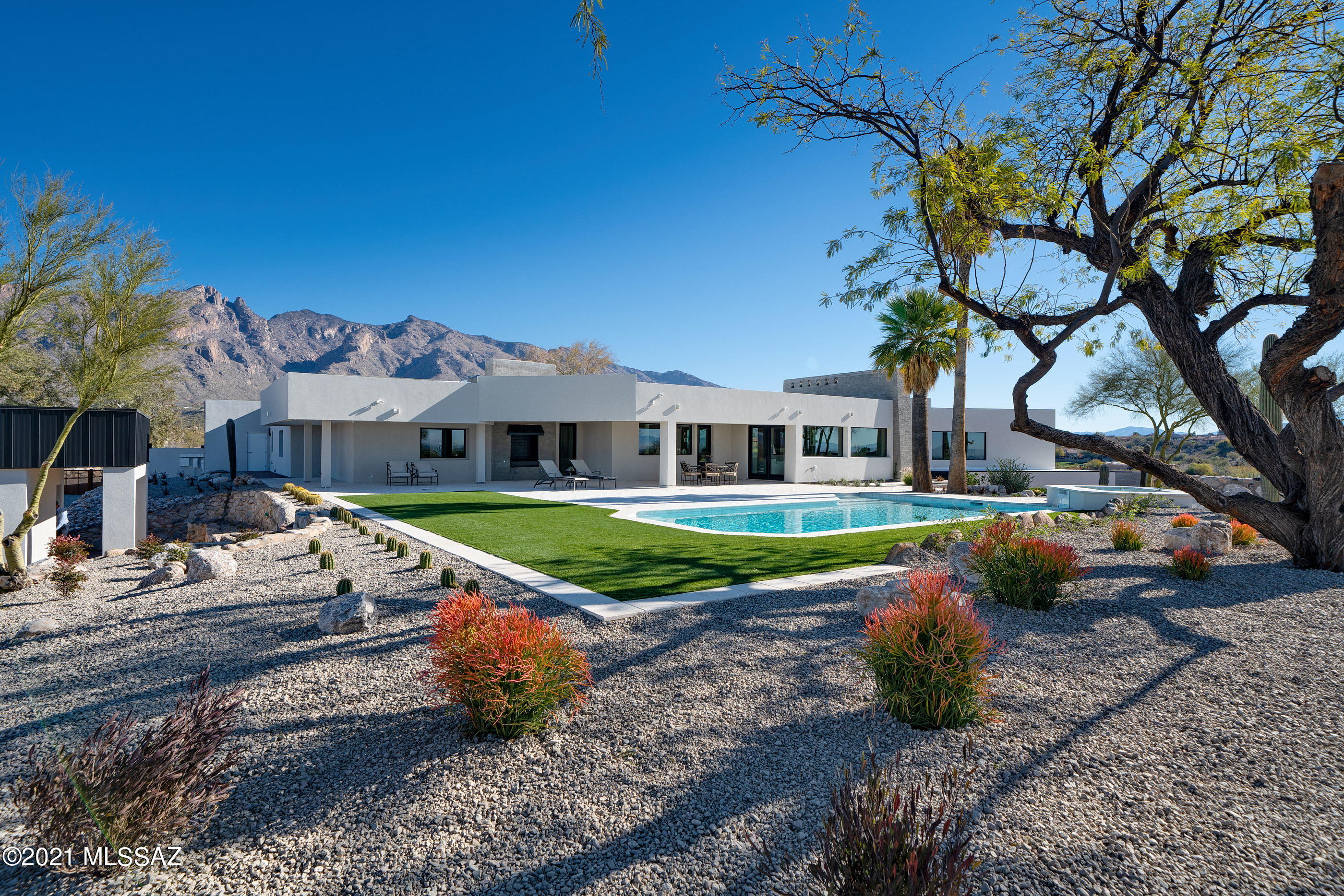 A 7,400 square foot new construction home and guest house anchors this unique and commanding 2.2 acre homesite, situated at the highest nearby elevation, spanning the width of two central view corridors. 
This privately gated estate is the Crown Jewel within the recently completed 5 home enclave, accessed through a long elegant drive to the expansive motor court. A striking anodized steel roof structure juxtaposes against the vertical mortar washed adobe walls, producing a strong graphic both horizontal and vertically. The main owner's level comprises 5,220 square feet, flowing continuously with the topography, while also adapting to the gentle cant of the hill top, creating volumes of shifting scale, while walls of windows expose the resplendent natural light, simultaneously maximizing mountain views to the North, city views to the South and golf course views to the East. 

The expansive transitional spaces blur the lines between the indoor and out, while bringing the awe-inspiring city and mountain views to the forefront of the experience. Showcasing masterful craftsmanship and exquisite detail offering a delicate balance of intimate and public spaces foster a dynamic living environment, with white washed oak floors that float seamlessly through the space, providing a gentle contrast to the smooth plastered walls. 

The exquisite chef's kitchen features custom walnut cabinetry, an expansive island with a breakfast bar, bathed in natural quartz stone, equipped with Wolf and Subzero appliances. The centerpiece of the dining room is a floor-to-ceiling "Cosmos Leather Granite" accent fireplace, with a glass wall perfectly framing Finger Rock and Catalina's to the North.

Among the six bedrooms and eight baths is the extraordinary primary suite with spa-style bath, large soaking tub, and glass walls that open to private and elevated view corridors stretching out over the greens of the La Paloma golf course. The owner's suite also features a private fitness studio, which has flexibility to be used in a multi-capacity. 

Exceptional entertainment and living offerings continue on the daylit lower level, comprising 1,830 square foot, complete with two secondary en-suites, a living room, office, dining room and a fully equipped kitchen, all opening onto 3 separate and private verandas. A 350 square foot studio guest house has been sited on the West end of the property, strategically terraced below the natural grade, to extend privacy for guests and owners alike, incorporating a generous bedroom, bath and captivating view corridors.

The site was specifically designed to preserve a generous portion of level ground allocated for outdoor living space, with the home opening onto a large covered terrace on the south end of the property, serving as an extension to the interior living spaces. Designed for the quintessential Arizona lifestyle, an outdoor kitchen, with sprawling landscapes, and swimming pool with an oversized jacuzzi, are conceived for year-round entertaining.

This ultra-private retreat, designed for the Foothills lifestyle, offers cutting-edge design, breathtaking views, and a timeless pedigree situated within moments of the Skyline and Campbell corridor offering acclaimed dining, shopping and entertainment.

Builder is offering a La Paloma Social Membership (Initiation Fee and a Year of Dues) to Buyer at Close of Escrow.