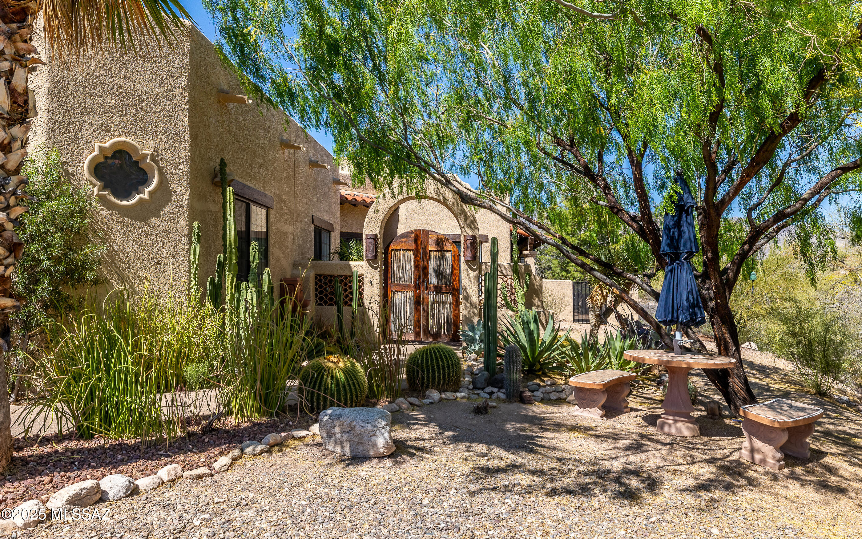 Come see this architect-designed Spanish Mission home perched on a ridge above Camino Real with direct Catalina Mountain views. Enter through a lovely courtyard full of mature plantings, then a beautiful carved-wood door, to a warm, welcoming 3-bedroom, 2-bath home. Softness and charm abound, with saltillo and wood laminate floors, unique saguaro rib and beamed ceilings, beehive fireplaces and Mexican tiles. Updated, functional kitchen with enormous island, gorgeous honed Quartzite countertops and induction cooktop. Have sweet dreams in a lovely, private Owner's Suite complete with beehive fireplace sitting area and door to the patio. Split bedroom floorplan with spacious rooms. Enjoy the outdoors on the wrap-around covered patio, or in the spa with a view!