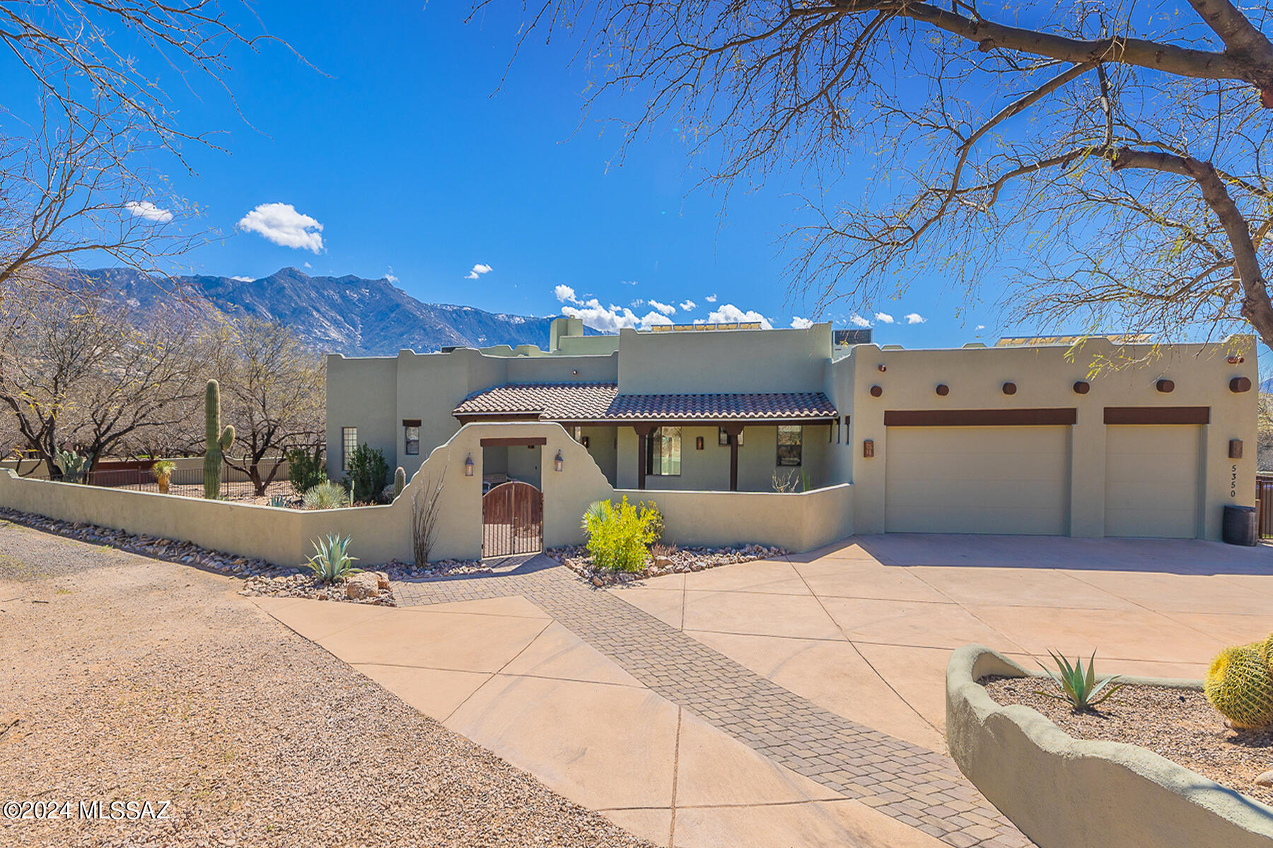 STRIKING CUSTOM HOME WITH BREATHTAKING VIEWS is near the world renowned Miraval Resort & Spa. Situated on a premium 1-acre end lot which backs to open space, this luxurious home offers 4 bedrooms, 3.5 baths (2,662 sq ft) and boasts Seller owned solar, 3 en-suite bedrooms off patio, 4th bedroom/office accessing front paver courtyard, and impeccably landscaped resort-style rear yard featuring 2 covered patios, raised dining patio with BBQ station, sparkling pool, plus trickling rock waterfall flowing to large koi pond. Enter to find luxurious Travertine tile in all main living areas and baths plus striking quartz countertops, custom alder cabinetry and overheight doors throughout. Formal living room is highlighted by a soaring wood beam ceiling, fireplace/media wall flanked by recessed bookshelves, and dual picture windows capturing the spectacular views. Gourmet kitchen boasts a curved center island, large dining area with picture window, staggered cabinets, stainless appliances including gas cooktop with handcrafted copper hood, plus spacious workstation and walk-in pantry. Luxurious Owner's Suite with patio access and open walk-in closet hosts a luxury bath with soaking tub and glass block, tiled walk-in shower. Powder room and extended laundry room with sink have quartz countertops. Retreat outdoors to the expansive rear yard featuring covered and uncovered patios which flow to a sparkling pool. Other thoughtful amenities include alarm, central vacuum, fire sprinklers, solar tubes, extended 3-car garage with storage closets and overhead racks, plus a dog run, circular driveway, and two fenced side yards (gated side yard can be used for additional parking). Recent updates include a high-efficiency zoned HVAC system, interior & exterior paint, high-end wool carpet in bedrooms, solar inverter, TESLA charger, water softener, reverse osmosis at kitchen sink, rear patio speakers and outdoor landscape lighting, plus brand new Kool Deck around pool. A true desert retreat!