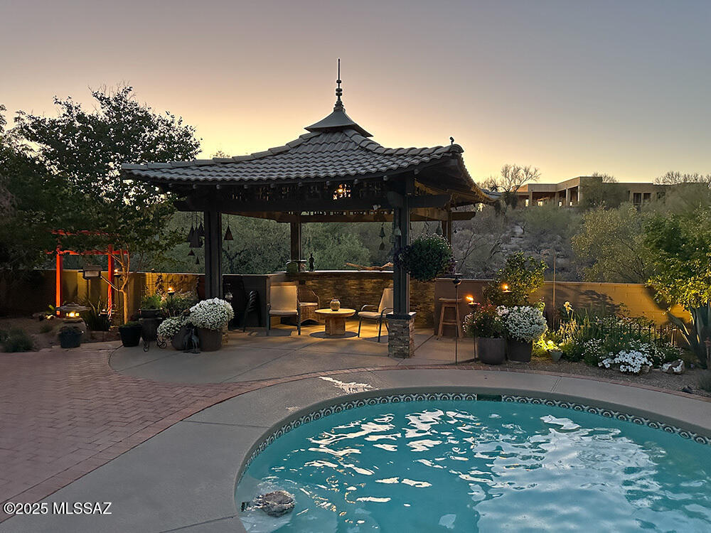 Nestled in the serene Foothills, this beautifully maintained 2,533 sq. ft. home is a rare find. Featuring 3 spacious bedrooms, 2.5 bathrooms, and a temperature controlled 2-car garage, this property is a true retreat with stunning natural desert surroundings.

Enjoy lush, meticulously landscaped grounds, complete with a tranquil pagoda and a striking Torii gate accenting the sparkling pool—perfect for relaxing or entertaining. Multiple patios encircle the home, offering private outdoor escapes at any time of day. The south-facing orientation provides captivating city light views by night and warm natural light by day.

Inside this beloved home, you'll find the kitchen that connects conveniently to the pantry/laundry room. The inviting family room flows from the main library/sitting room ideal for quiet moments or flexible living.
Quiet and secluded, yet located 5 minutes from shopping and 20 minutes to the University of Arizona. Click on "Documents" for floor plan. Don't miss your chance to own this timeless property. Put this one at the top of your list!