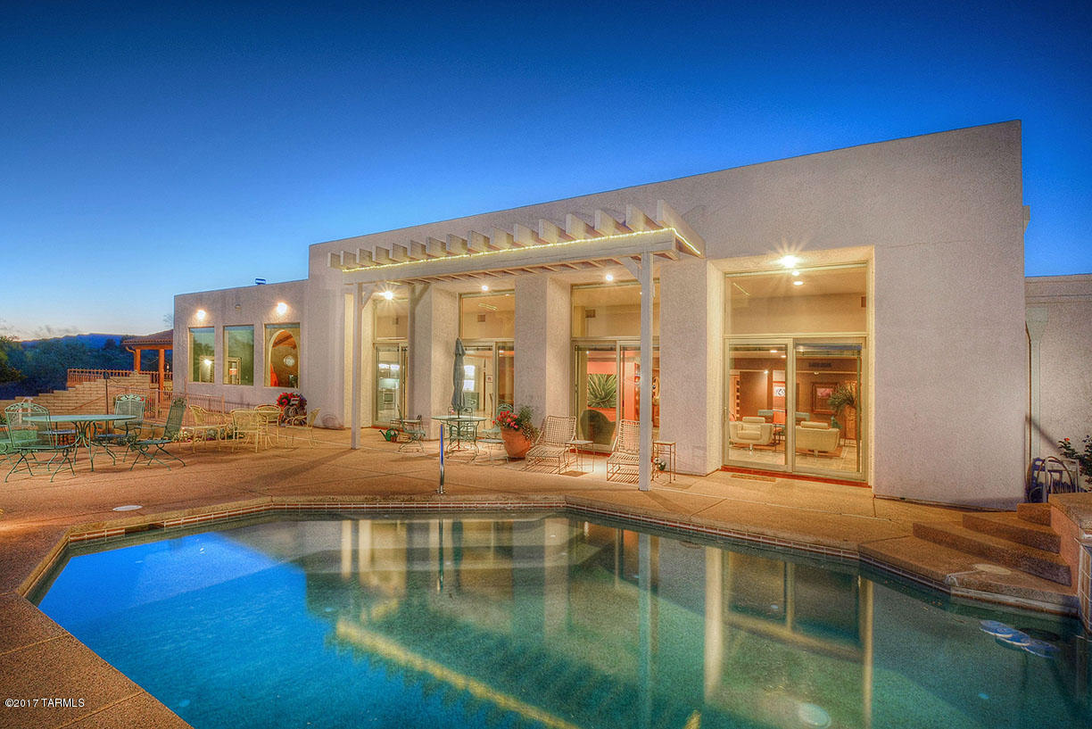 As you become ready to redefine life on your own terms, consider this luxurious estate right in the center of Green Valley! Discover a desert oasis where you can enjoy absolute privacy while relaxing on your pool deck and still walk to town for your morning coffee. Combining elegant, refined interior and outdoor spaces with gracious proportions and unbelievable views, this home offers you the indoor/outdoor lifestyle you have been waiting for! Sitting on over 3 acres and offering some of the most incredible views in Southern AZ, this 6200 sq ft estate's enviable list of amenities includes 4 bedrooms, 4.5 baths, magnificent great room, media room , den, gorgeous butler's pantry, personal gym, 2 laundry rooms, 4 car garage, pool and spa. One of the en suites is located in a separate wing of the home and includes its own living area, full kitchen, patio and garage, making it the perfect retreat for long term guests, extended family or care takers. With no HOA, the guest wing could even be used as a Bed and Breakfast for those looking for a new challenge in their retirement!
A 10 ft addition to the back of the home resulted in an open floor plan which focuses on the stunning view and is custom tailored for entertaining. Over sized windows installed along the length of the expanded living area are all about bringing the "Outdoors In" and framing the Santa Rita Mountains. The expansive outdoor living area is host to a tranquil pool and spa and numerous patio areas and gardens for entertaining. Warm modern tones on the walls are artfully highlighted by unique custom lighting. Luminous neutral travertine tile flooring and natural stone create the perfect organic balance on the floors and in the baths.

The kitchen is beautiful AND functional with enough counter and seating space to accommodate the largest celebratory events or a growing family's needs. A wooden ceiling and beams add an authentic touch, while soft turquoise lacquered cabinets finished with a high gloss car paint bring a modern edge. Frosted glass self-lighting storage, top of the line stainless appliances, a huge center island, and crystal pendant lighting add a little bling. Directly off of the kitchen, the butler's pantry offers ease and functionality with its additional storage and counter space, and an extra sink and refrigerator.
The luxurious and inviting master suite offers heated bathroom floors, arched wooden doorways, a spa shower, and personal laundry. Work out in your en-suite Gym with its mountain views and then enjoy gazing at the stunning gardens from your oversized soaking tub!

The media or gathering room exudes warmth with its impressive floor to ceiling beehive fireplace, wood ceiling and beams, beautiful built-ins, entertainment bar, and views through the archway which will at times leave you breathless. You will cherish family movies or intimate time with friends in this multi-functional space. 

Whether your lifestyle is based on family, entertaining, or both, this elegantly designed and artful home is meant for a passionate and discriminating owner who is ready to embrace the modern desert lifestyle.