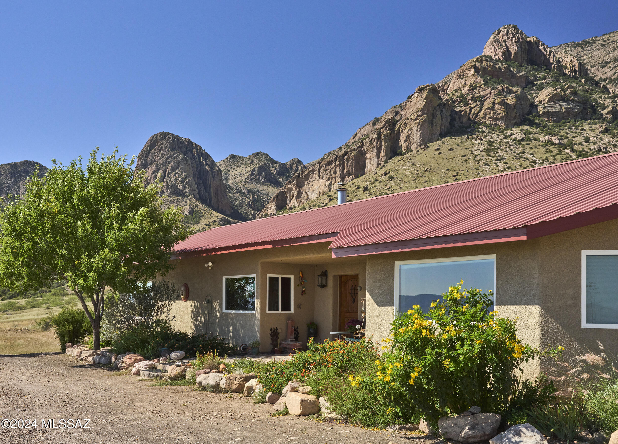 Tucked at the base of the Chiricahuas in scenic Portal, this custom 2,391 sq ft home blends comfort, efficiency, and Southwest charm. The open great room centers around a spacious kitchen with oversized island and walk-in pantry--perfect for gathering. Split floorplan offers privacy, with a serene primary suite featuring ensuite bath and walk-in closet. Enjoy a cozy library with custom cherry shelving, wood-burning fireplace, and energy-efficient in-floor heating (5 zones). Large windows frame mountain views and natural light throughout. Outside, a circular drive, fenced acreage, drainage improvements, and 200 amp service to a lower pad offer flexibility for expansion. 3-car garage (1,080 sq ft). Minutes to Portal & Rodeo.