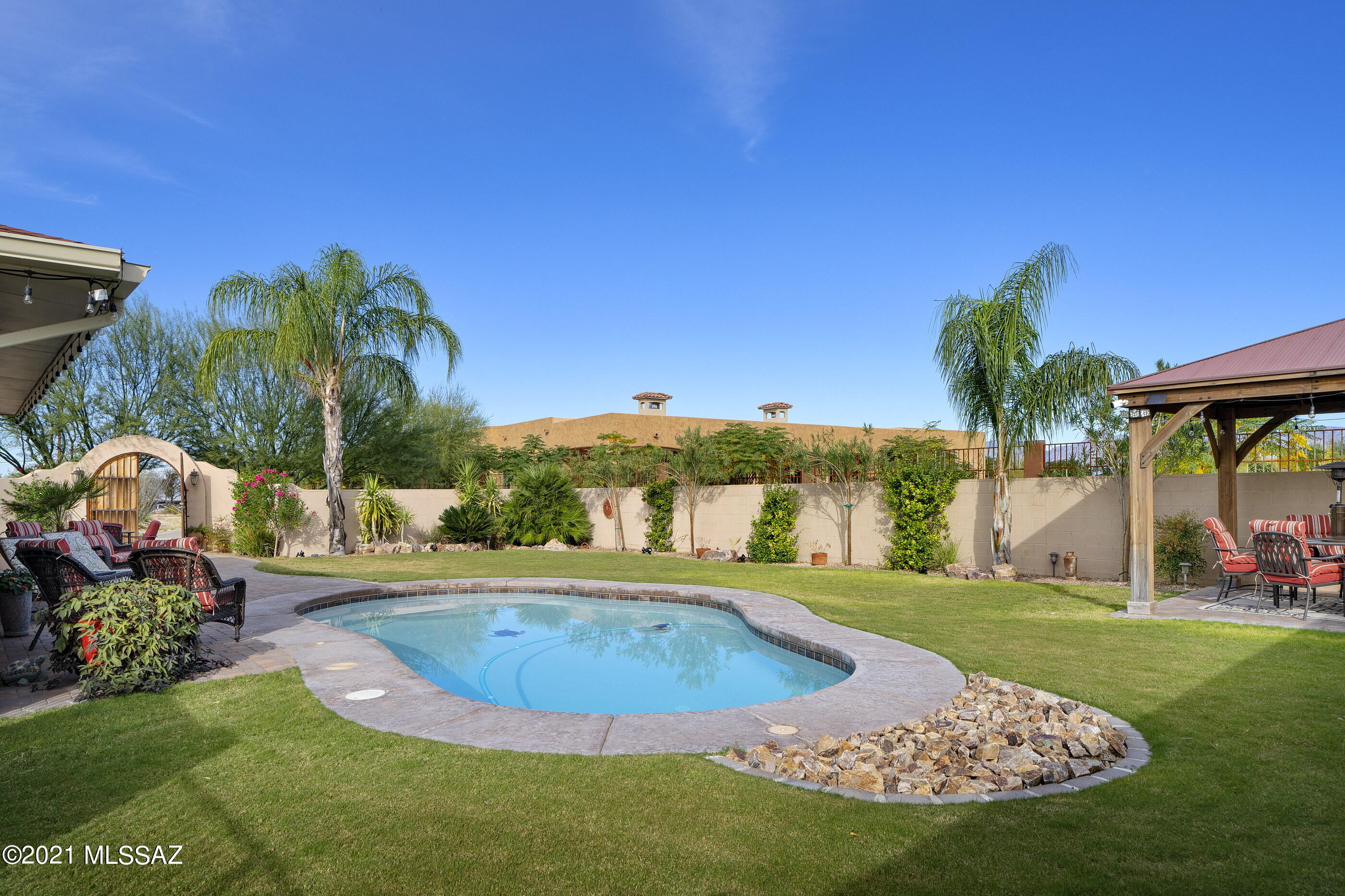 Beautiful custom home on over an acre in a quiet rural setting yet minutes from shops & restaurants. Enter through the lovely gates to a peaceful courtyard w/stunning mountain view. Welcoming mosaic tile foyer opens to large great room featuring floor to ceiling windows, expansive brick fireplace, polished ceramic tile floors & open concept living. Chef's kitchen w/SS appliances, gas cooktop, dual ovens & island w/seating. Nice split-bedroom floor plan w/primary bedroom located down private hall w/en suite bath & spacious walk-in closet. This home is made for indoor/outdoor entertaining w/French doors that open completely leading to the backyard oasis w/large grass yard, multiple seating areas, sparkling pool & covered ramada. 2-car garage & RV parking w/electric & dump facilities. No HOA!