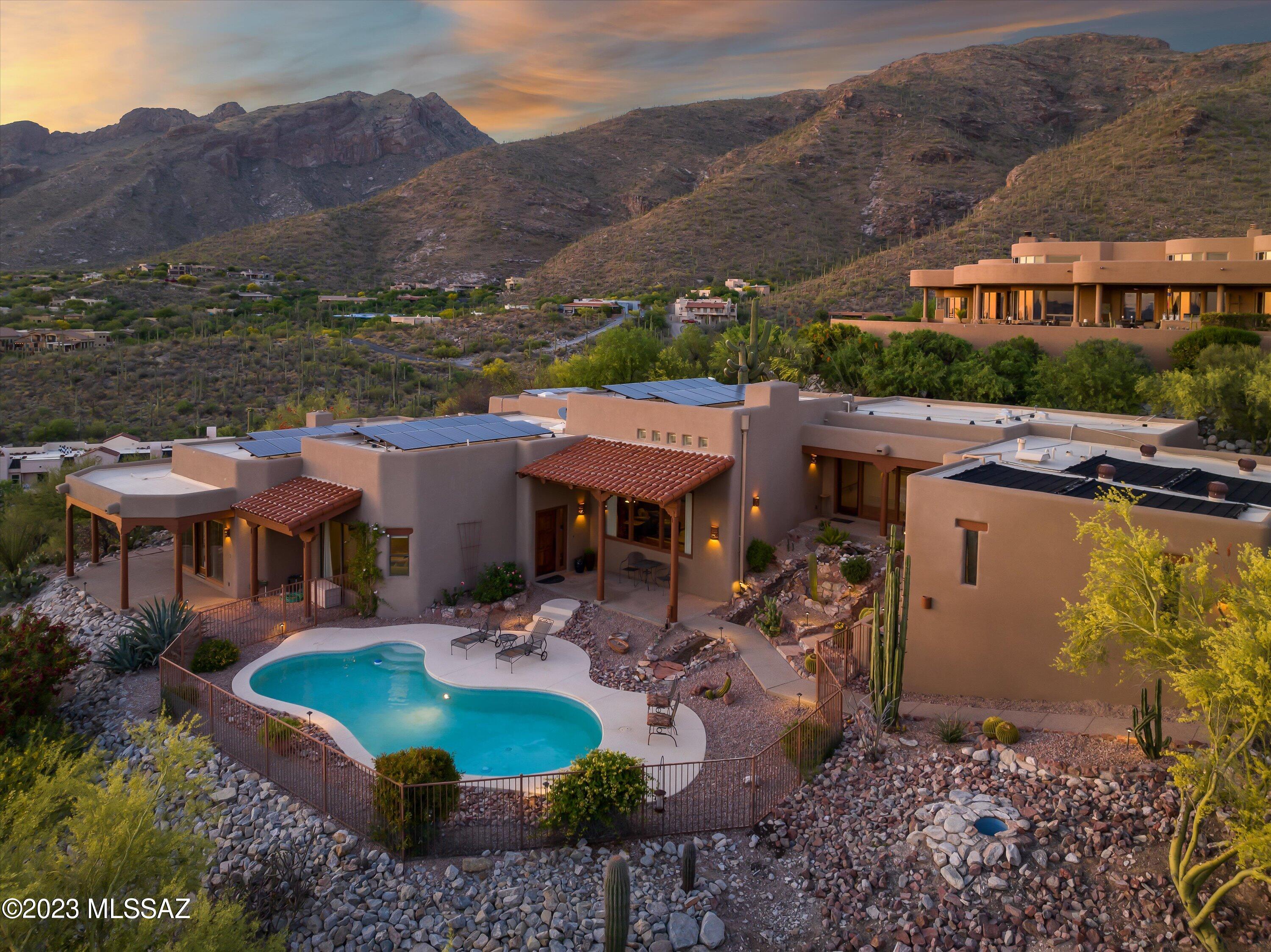 Prestigious foothills community w/manned guard house gated entry. This expansive home has plenty of space to entertain and offers room to spread out. Separate living room with wet bar and family room with the most amazing city views! The primary suite features a cozy fireplace, access to a covered patio, and an en-suite bath complete with a walk-in closet, jacuzzi tub and separate walk-in shower w/dual shower heads. The kitchen offers lots of cabinets and counter space, an island and a breakfast bar. You'll love the sparkling, heated pool, the 3 car garage with extra workshop space, and spectacular views! There is SOLAR on this home, so take advantage of that Tucson sun and enjoy low electric bills! Minutes to La Encantada shopping & fine dining.