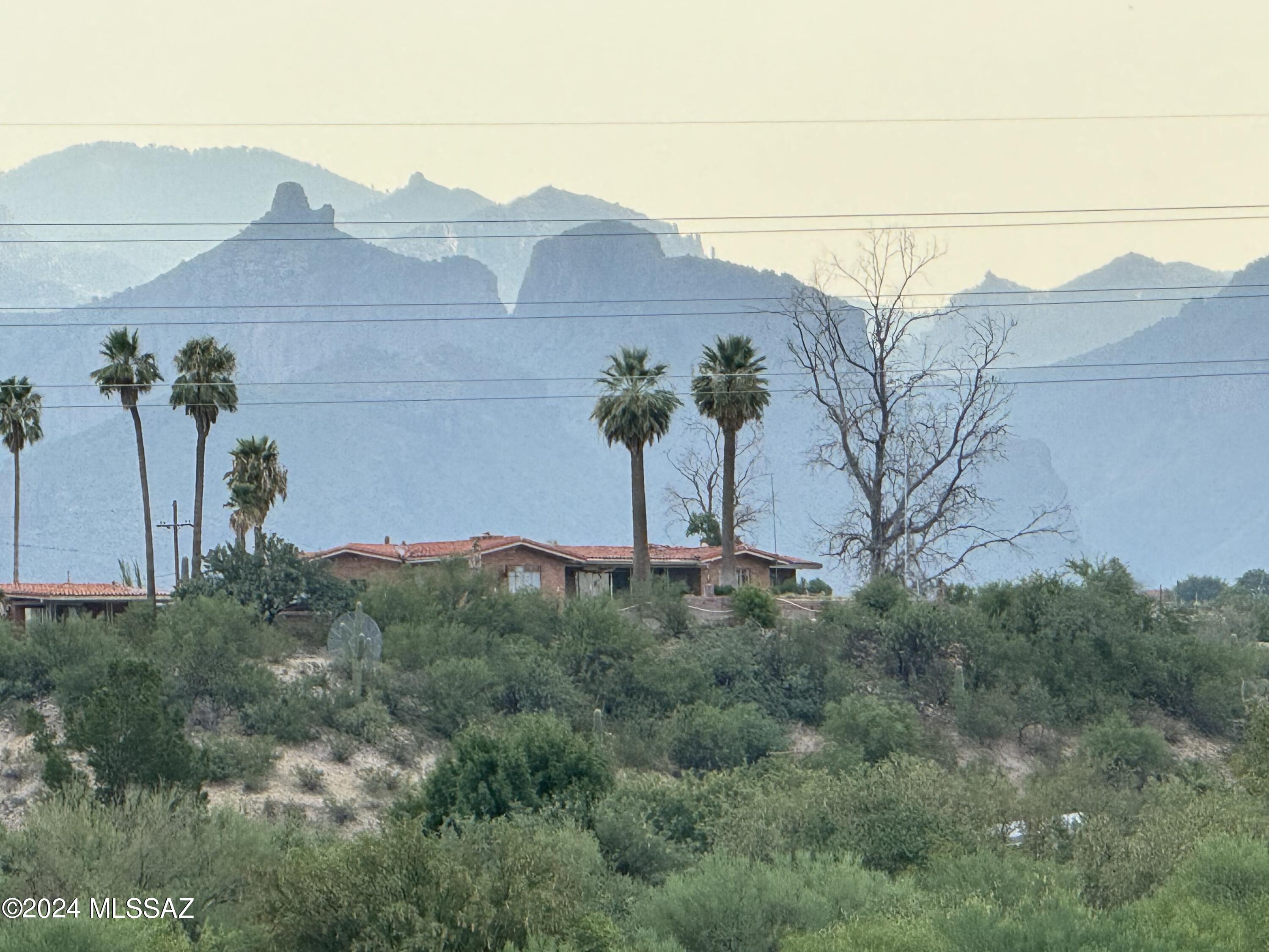 Diamond in the rough! This is the investment opportunity you've been craving. Perched on 3.5 acres on the first ridge above the Rillito River, this adobe home offers unobstructed panoramic mountain, city, and sunrise to sunset views. The 3-bedroom, 3-bath main house includes a maid's quarters/nursery off the primary suite. The split floor plan could be reimagined into three ensuite bedrooms plus a powder room. The great room features wood-beamed ceilings, a cozy fireplace, and opens to a vast covered patio perfect for entertaining. Property highlights include a pool, pool house with kitchen and bath, and a guest house ideal for extended family, office, or rental use. Close to shopping, dining, and the Loop  multi-use path.