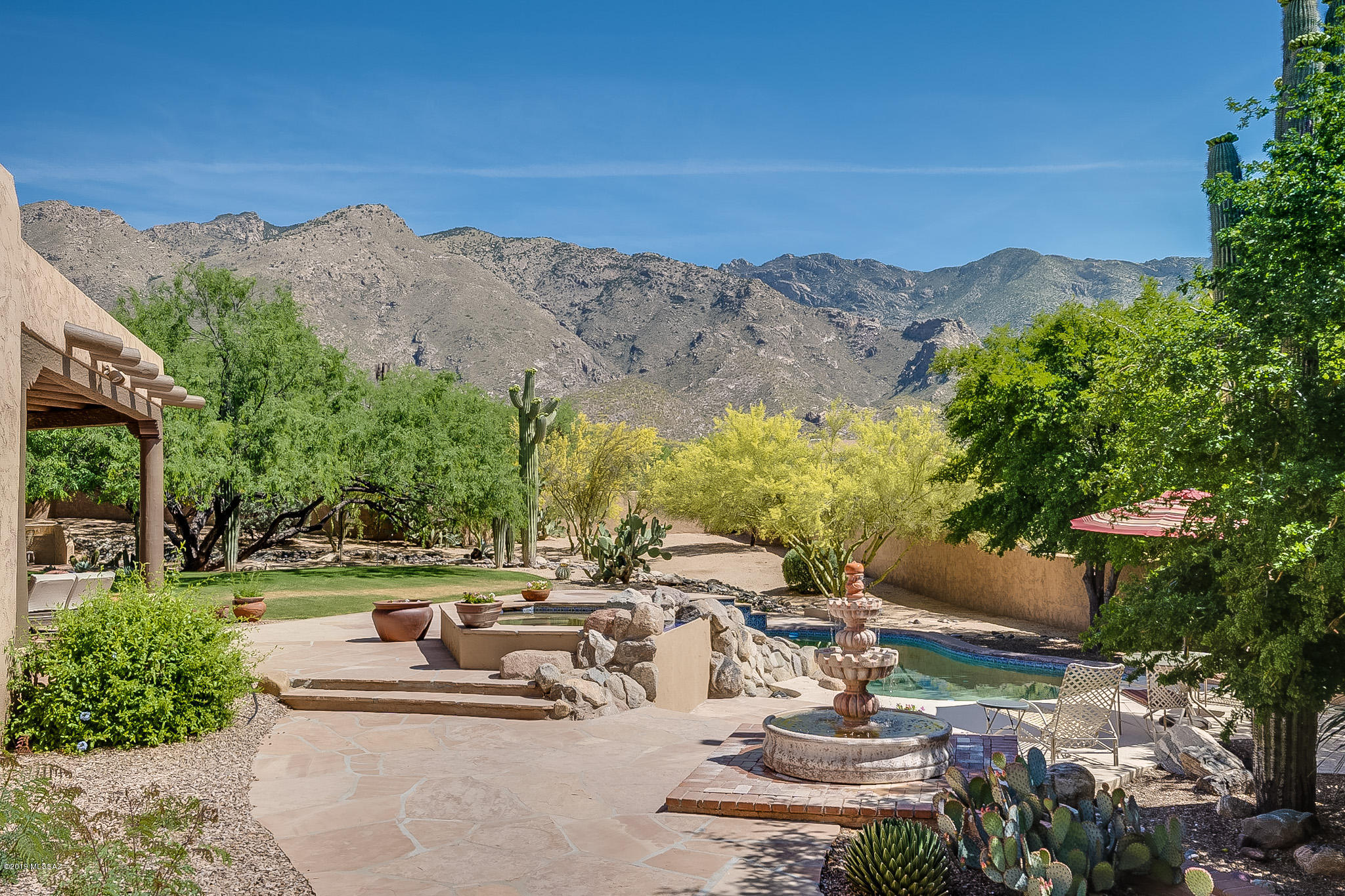WONDERFULLY CRAFTED FOOTHILLS SANTA FE sited on a 1 acre cul de sac lot with DRAMATIC MT. VIEWS! Just some of the features included are, courtyard entry with a large fountain, 8 ft. double custom wood / iron entry doors, MASONRY STUCCO construction, MASSIVE hand hewn ceiling beams accented with Lattia's. Lintels & Vigas, hand-wrought iron hardware, butler wire brushed cedar interior doors, art niches abound. The spacious Kitchen is appointed with SUB ZERO, MONOGRAM, KIT. AID, & PROFILE appliances all open to a large family room with a beehive fireplace! New cook top and granite accent center island counter top. The Master bedroom offers a beautiful sitting area with its own bee hive fireplace and 2 covered balconies! The den/library with ceiling to floor hardwood bookshelves,  see link.... A gorgeous coffered dining room ceiling with a custom paint design. 3 car garage that has one bay separate from the other two that is over sized, air conditioned and heated, it could be used as a art studio, guest/ 4th bedroom, man/women cave, professional office space, or workshop! The backyard is an Oasis with a large lush grass area, a spa & waterfall feature adjoining the swimming pool with flag stone decking designed with nature in mind. Around back is a gated entry to a stairway to heaven roof deck to view those wonderful night time city lights! And best of all are the up close mountain views of the Catalina's from multiple viewing areas of the home and backyard!