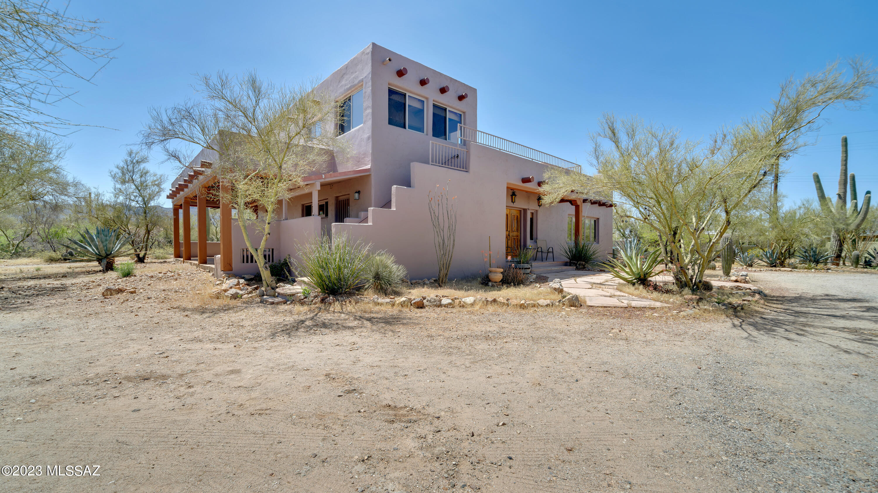 Artistic and Charming Santa Fe home nestled peacefully among towering Saguaros on flat usable 3.14 pristine natural desert acres. Custom home with 24'' adobe walls, wood plank and Viga ceilings. Inviting beehive fireplace in spacious great room, concrete and flagstone floors. Enjoy the lovely flagstone patios with wood Vigas, and the wonderful rooftop deck with magnificent 360 views of the city and mountains. The property includes a well-situated private -Guest House- 883 sf 1/1 - complete with full kitchen and carport. Only a 3-minute drive to Christopher Columbus Park for boating, fishing, BBQ, and entry to the many miles of paved bike path to enjoy safe and scenic cycling, as well as quick access to Silverbell Golf Course, driving range & practice area. Located in a great neighborhood