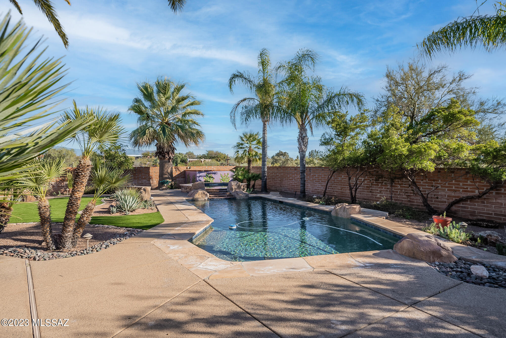 A stunningly remodeled and rebuilt gem in the Tucson Foothills with an elegant backyard paradise and many custom features awaits its new owners. The entire home has been largely renovated in all details—new kitchen, new baths, new paint inside and out, new knotty alder custom cabinetry and doors, new window coverings including plantation shutters—and is ready to AWE you. It provides excellent privacy and sweeping views of Tucson's glorious mountain ranges. The long paver drive leads to a well-sized entry parking area for your guests, and a new custom front door. Stop to view the ''Old Tucson'' custom tile artwork seen as you enter the home, truly one-of-a-kind. The new kitchen has 3mm ''citrine'' quartz counters, abundant rich knotty alder cabinetry with pullouts and lots of deep drawe new high-end appliances including a five-burner gas cooktop and a wine refrigerator, two islands, and a generously sized breakfast area. Chef's dream! The adjacent family room enjoys a fireplace, plantation shutters and French doors out to the wrap-around terrace and elegant pool and spa, and includes a large dining area. With a large terrace that wraps around the rear of the home and includes two stunning fireplaces with more custom one-of-a-kind tilework (Do see the photos!) and a large outdoor kitchen with a fabulous BBQ unit, two burners, a sink and under-counter refrigerator, and a  long counter with a heater for chilly evenings, this is quite the spot to entertain! Step down broad steps to the handsomely landscaped yard with "grass" area and a graceful pool and spa. The home also has completely rebuilt adobe wall for safety, New pump filters, New irrigation system front and back, Built in cabinets in hall alcoves, New hanging lights, and New hearth and mantle. And enjoy those sweeping views in multiple directions of Tucson's gorgeous mountains and city lights. While you are outside, take a look at the separate casita, also featuring new quartz counter and cabinetry. Back inside the main home, the two guest bedroom both have walk-in closets and share a handsomely remodeled bath with a newly tiled glass-front shower. The Owners' Suite has French doors out to the terrace and a remodeled bath that includes new double sinks in new quartz counters and more rich cabinetry, and a glass-fronted walk in shower with a Rainbird showerhead. In the oversized two-car garage, behind a "barn" sliding door, is the remodeled laundry featuring more new quartz counters, a new laundry sink, more new cabinetry and new washer/dryer. The laundry room also features a large chest freezer, and a mini-split HVAC system. 
Home is secured by digital WiFi smart locks/ garage door access and cameras.  A terrific opportunity to live in the heart of the Foothills,and lots of nearby amenities and excellent medical care. Welcome to Foothills living at its best!