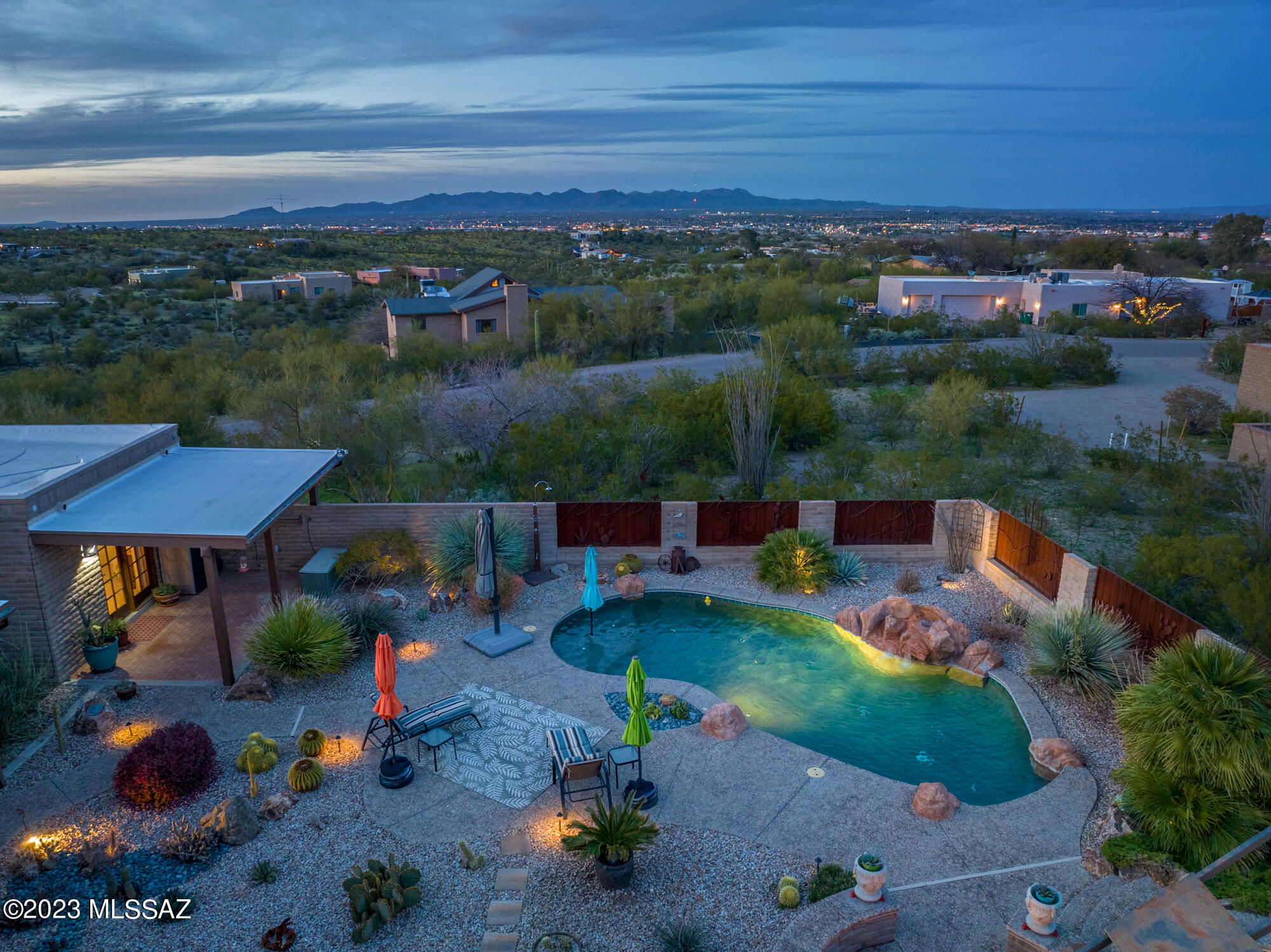 Seller will consider offers in the range $1,000,000 to $1,075,000.   To walk into this custom home is to fall in love!  Timeless design and custom features, built to  capture the desert surroundings and sited perfectly atop a raised corner 1.08 acre lot to capture the amazing Mountain and Twinkling City Light views!  The grand foyer with cathedral ceiling welcomes you into this amazing home.  Gourmet kitchen has it all! Huge center island features a built-in double wine cooler, new induction cooktop, 48'' custom sink and faucet, stainless steel wall oven/microwave built-in unit, newer dishwasher and French door refrigerator, extended breakfast bar and highly upgraded slab granite countertops.  Great Room features a cove ceiling plus a gas fireplace with Heatilator fan  and built in banco seating plus wired for sound inside and to the patio. Separate dining room features built in benches with southwest flair.  Anderson and Pella windows and doors throughout.  All bedrooms feature walk in closets and ceiling fans.  Amazing Owner's Suite has a private covered patio, huge walk in closet and amazing spa-like bath with custom cabinetry, pull out laundry bin built in, travertine multi-head walk in shower with niche and seat, dual vanity with granite countertops and basin sinks. 
Every light in the home has been replaced with LED lighting.  All window coverings replaced in last 2-4 years.  Custom electric roll down shades placed on West facing windows/doors for the warmer months of the year.  Upgraded tech runs the pool, main garage door and irrigation... all on wifi and app run.   
Entertaining is a dream with multiple covered patios open to the gorgeous resort-like backyard with Pebbletech Pool, Spa, Firepit and amazing Outdoor Kitchen.  Whimsical, tropical theme pool bath is accessed from backyard plus outdoor shower to rinse off before coming in.  Custom artistic metalwork throughout the property accents the solid block construction.  Huge RV carport (see floorplan for size) and approx 6 car tandem garage for all the toys! Extensive Beyond Brick paver driveway, landing and circular drive make for great curb appeal! 
Originally built by a builder for himself, the bones here are above and beyond the average home, remodeled, customized and upgraded even further in years since and meticulously maintained-- you will be hard pressed to find more value in a home than this one! There is something special at every turn!