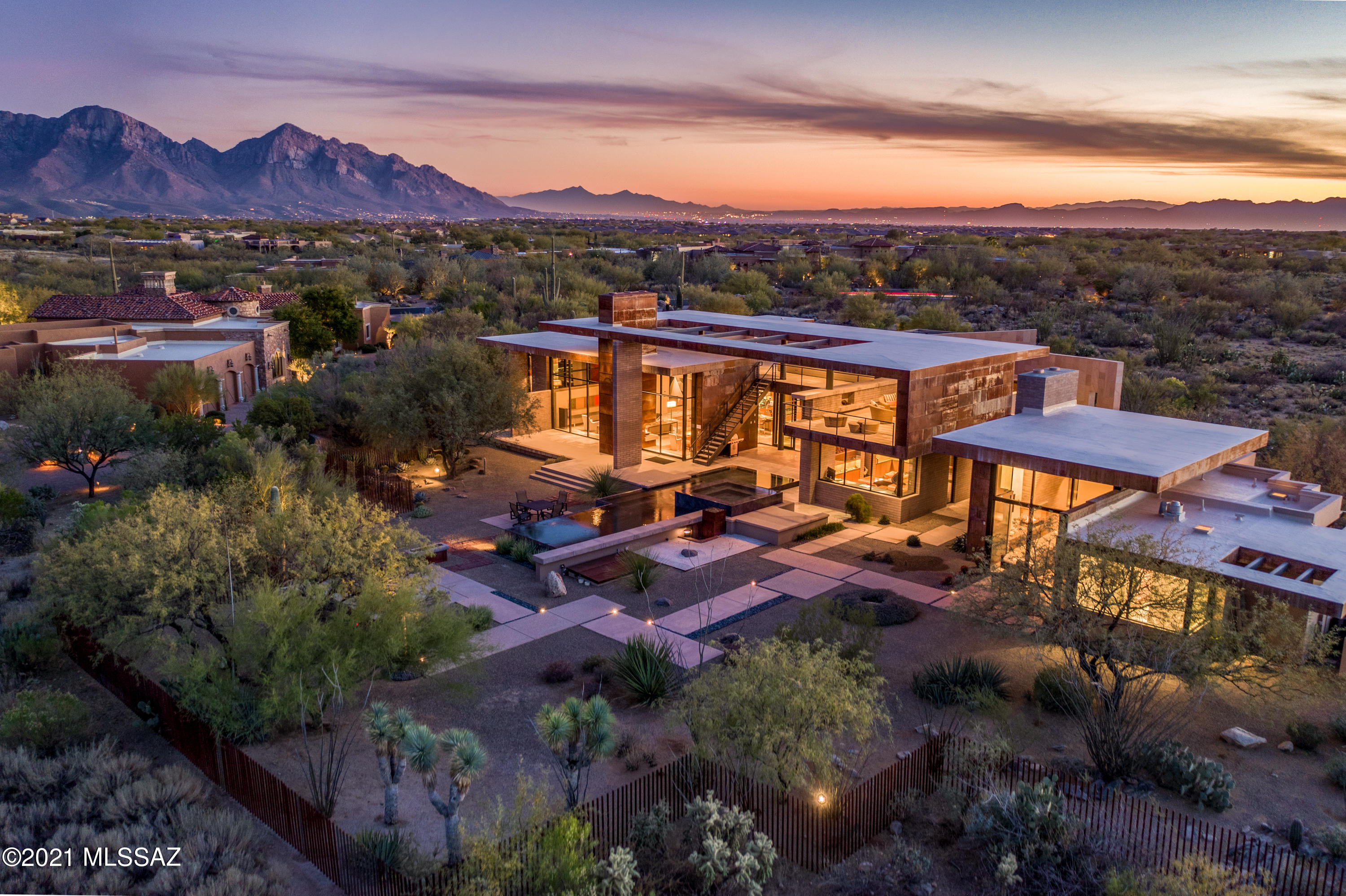 Zen Contemporary an Entertainers Dream Home | Enter through outdoor halls layered with neutral welcoming sandstone tiles leading you to walls of glass bringing the outside in. Pivoting oversized grand door opens to expansive spaces with a breathtaking first glance. Envisioned by Kevin Howard and tastefully appointed by a Hollywood Interior Designer with superior organic materials including but not limited to Sabbia Limestone flooring, Honed Black Granite, Kozmus Granite, Hansgrohe fixtures, Decor Appliances, Subzero Refrigerator, High Volume Ice Maker, Dual Zone Wine Cooler and Beverage Cooler to reference just a few. Expansive spaces and disappearing glass walls that seamlessly connect the interior to the tranquil patio & negative edge swimming pool & spa area with several terraces including one of the most spectacular covered roof decks built in the development - complete with fireplace, TV entertainment and views in every direction from Golf Course, Catalina Mountains to Downtown City Views. Three sizable bedrooms with ensuite bathrooms. Gracious office in main house includes a Rare Limited Edition Stow-Davis restored desk (1 of 10).  Cozy master bedroom with glass bead fireplace, masonry wall, secondary laundry in master closet and expansive master bathroom with thermostatically controlled radiant floor heating including shower bench (guest bathroom floors also heated with system). 
Detached guest house furnished with murphy bed w/custom cabinetry, burlwood game table & leather chairs.  Home is fully furnished including artwork - See  documents tab for complete list of items that convey.  (