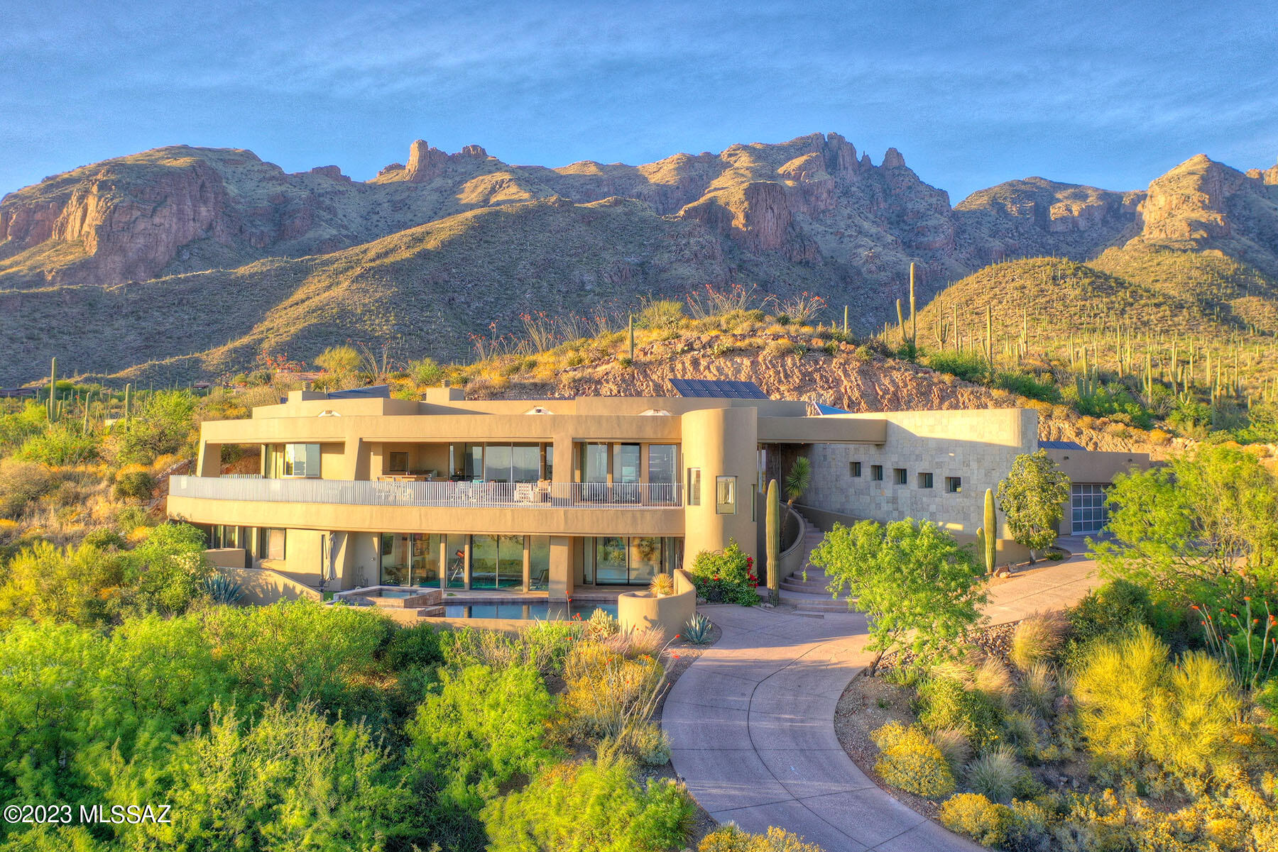 A visually stunning 5,878 sq. ft. contemporary masterpiece, designed by renowned architect Ron Robinette, is nestled on a high foothills lot at the end of a quiet cul-de-sac in gated Foothills II and offers sweeping 180 degree Tucson city views! The spectacular estate is a fusion of architecture and sophisticated amenities wrapped in finishes of limestone and glass, accented by designer touches and lighting. Highlights of the 4-bedroom (plus office/den), 4.5-bath home includes a grand entry & foyer, high ceilings, walls of glass overlooking the entire city, and extensive use of stone flooring. The spacious living room, open to the dining room and the kitchen offers a corner fireplace, walls of glass and access to the 1,200 sq. ft. covered balcony. The balcony with outdoor kitchen and dramatic views is perfect for entertaining guest. The uber contemporary gourmet kitchen provides designer appliances including a gas cook-top, granite & natural stone counter tops, a walk-in pantry and a breakfast area. The gracious primary suite features a fireplace, balcony access, and an expansive bathroom complete with dual walk-in closets with built-ins, dual vanities, a spa tub and an oversized glass steam shower. The lower-level guest suite offers a generous family room, a bedroom, a bathroom, a kitchenette and a exercise room. Walk out from the guest suite to professional landscaped grounds, an outdoor fireplace, a built-in BBQ, and a negative-edge Pebble Tec pool & a spa with a spillway. Additional features include an owned solar system, a oversized 3-car garage, and an abundance of storage. District #16 schools.