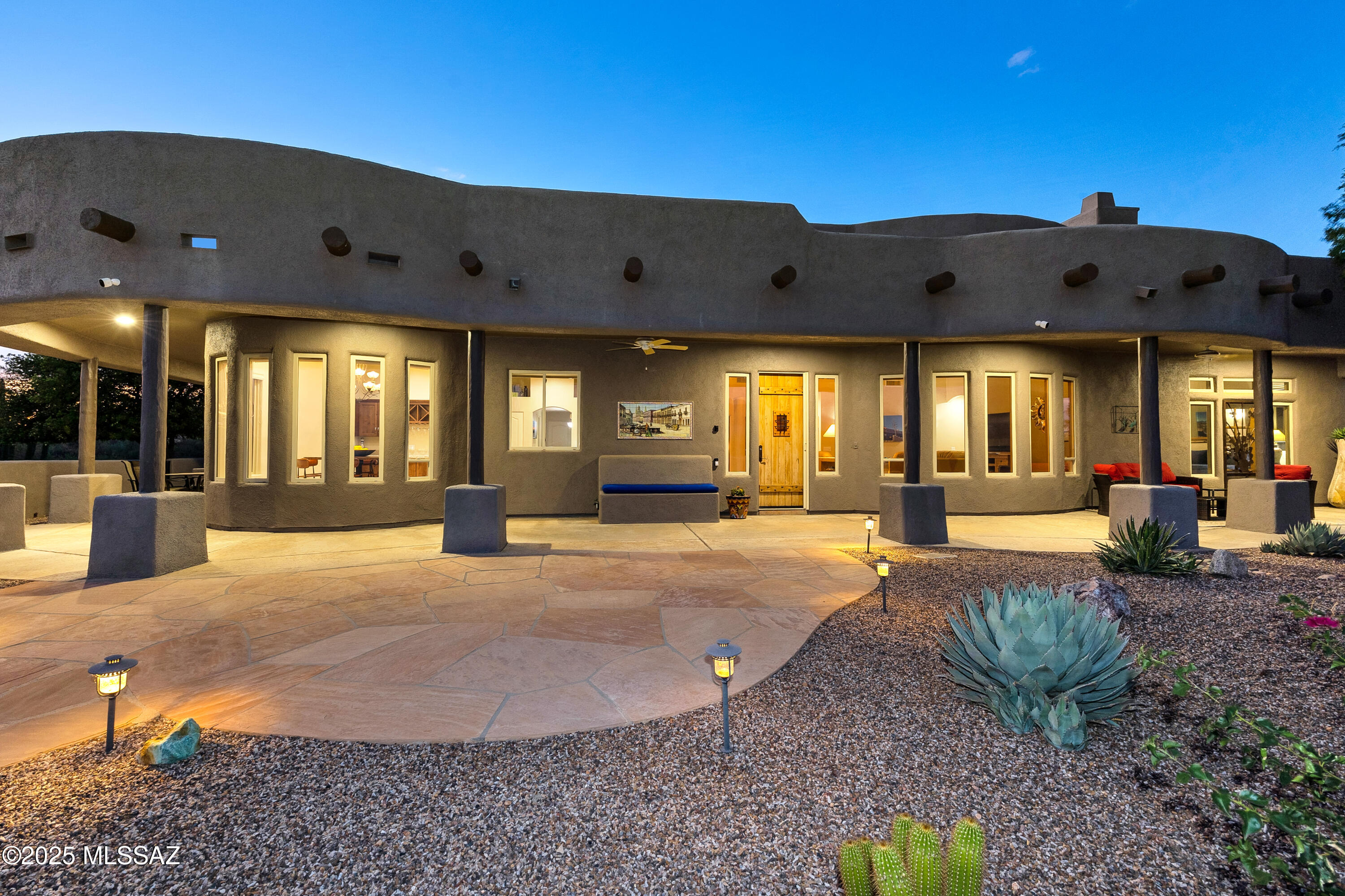 Discover an extraordinary sanctuary where luxury meets nature's grandeur. This exceptional residence commands breathtaking panoramic views of the majestic Santa Rita Mountains from every living space, creating an ever-changing tableau of natural beauty that serves as your daily backdrop. Tremendous curb appeal is created by an extraordinary front courtyard featuring an expansive patio that perfectly frames the spectacular mountain vistas. This magnificent outdoor space serves as your personal theater for morning coffee rituals or elegant evening gatherings around the fire pit, where the Santa Rita Mountains provide a dramatic and ever-inspiring stage. Inside, drama unfolds at every turn. Soaring wood-lined ceilings create cathedral-like grandeur, while highly customized windows frame the mountain views like carefully curated artwork. Architectural poetry is exhibited through arched passages and thoughtfully placed niches, each detail crafted to enhance your daily rituals. An open kitchen flows effortlessly into the living area and features thick-slab, natural-edge granite that seems to glow against rich chocolate cabinetry, creating a space where culinary adventures and conversation flow as naturally as the mountain breezes.
The dining area presents perhaps the home's most stunning moment: uniquely designed windows that transform the Santa Rita vista into living art, making every meal a celebration of place. A commanding fireplace anchors the great room, where mountain views pour in through expansive glass, creating an ever-changing backdrop for life's most precious moments to the sophisticated interiors. Three bedrooms and three baths plus a den offer endless possibilitiesguest retreats, creative studios, or quiet sanctuaries for reflection. But it's the backyard where this home truly reveals its soul: your private desert spa featuring a built-in outdoor kitchen, mesmerizing fire pit, entertainment area with outdoor television, and an oversized hot tub spa. Complete privacy transforms this space into your family's magnetic gathering placewhere celebrations feel more meaningful, conversations run deeper, and memories are etched against the timeless beauty of the desert horizon.
This isn't just exceptional real estate; it's your personal gateway to a life lived in harmony with one of nature's most inspiring landscapes.