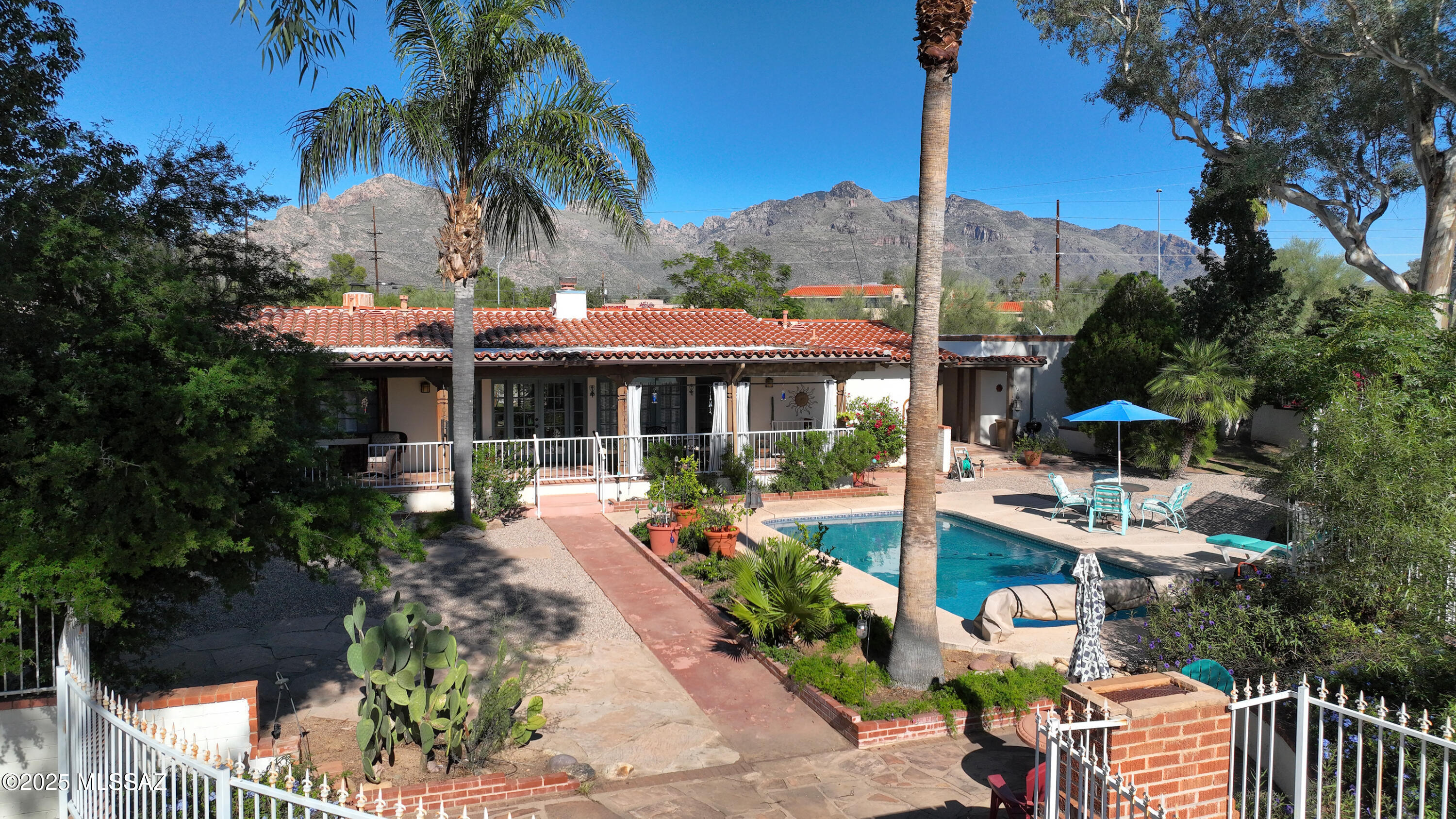 This beautiful southwestern home offers mountain views, vintage charm and plenty of character creating an incredible retreat in the sought-after Casas Adobes neighborhood! Lovely courtyard entry welcomes you inside where you'll find beautiful wood ceilings, 2 stunning fireplaces and a remodeled kitchen with hickory cabinets & SS appliances.  The living room boasts a huge picture window framing the view. The family & dining areas open to the backyard through double French doors. Outside, entertain guests in the lush backyard w/pool, extended covered patio, BBQ/firepit and banco seating.  Luxurious primary has sitting area, claw-foot tub and walk-in shower.   Newer masonry wall surrounds the entire 1.25 acre property. 2-C Gar plus 2-Car caport and private gate round out the home.