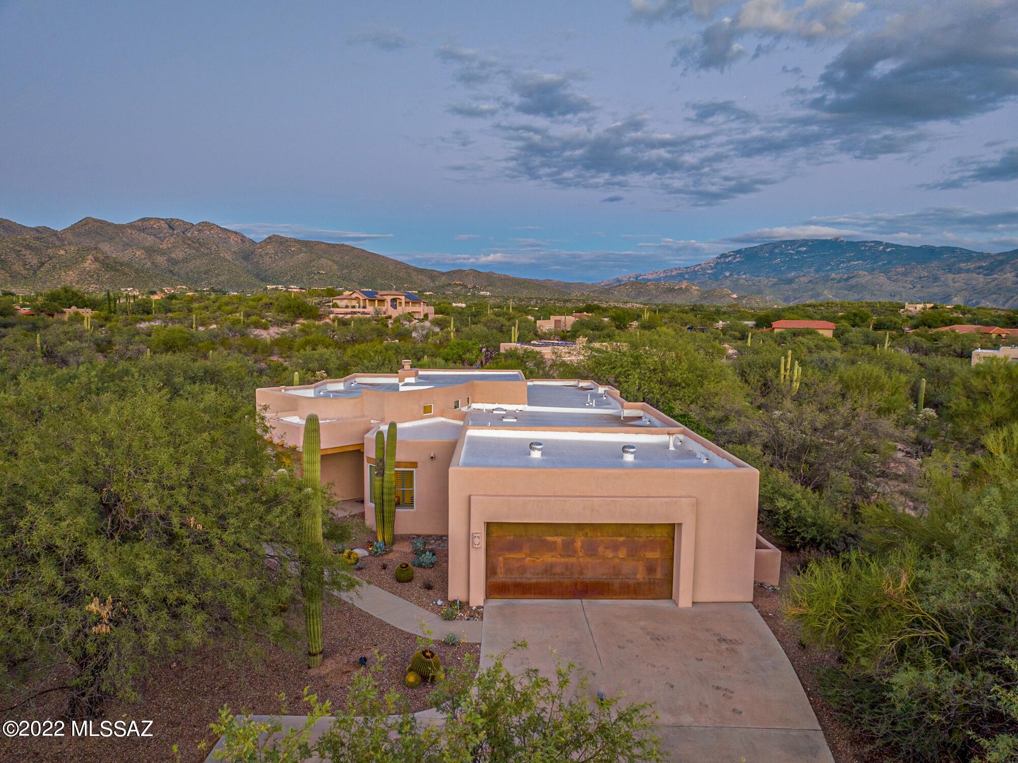 The perfect SW home, set tranquilly back in a mesquite bosque surrounded by nature and mountain views of the Catalinas and Rincons as a pool backdrop! This custom home is architect designed and built with maximum windows to take in views in most directions. The greatroom features soaring ceilings, gas fireplace and a wet bar. The kitchen is loaded with white cabinets; update the hardware for a personalized look. The prep sink, double ovens and WI pantry aid home chefs. A huge ensuite primary BR offers direct access to the salt-water pool and spacious covered patio. It also boasts an enormous WI closet and double vanity. Two other bedrooms and a bath in a separate hallway provide privacy. A 4th BR is ideally located to double as home office/den. Store tools and toys in an oversized garage. Make this beautiful suburban neighborhood your home!