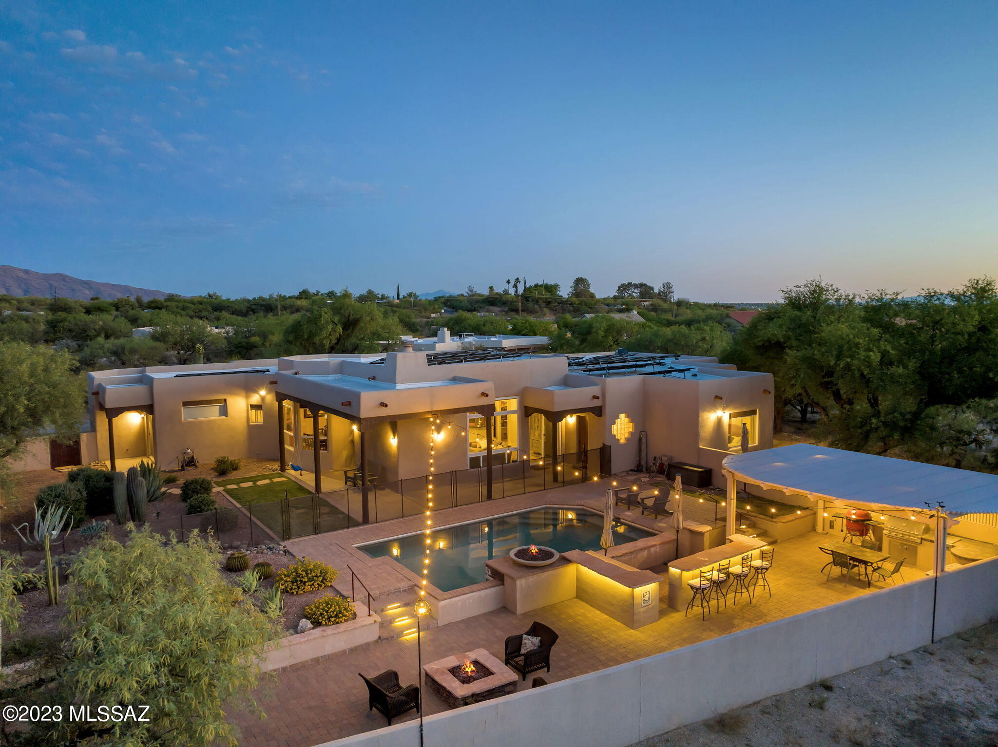 Phenomenal NE Santa Fe style contemporary home with near-panoramic views of the Catalina and Rincon mountains!  This 5 bedroom/ 3.5 bath, 3,002 sqft beauty sits on 1.23 acres, and has no HOA!  Plenty of room for an RV.  Enter through custom brushed wood double doors into an open floorplan with soaring exposed log-pole beam ceilings, beehive gas fireplace, and stunning mountain views.  The fabulous kitchen features chiseled-edge black granite countertops, oak wood cabinets, GE profile stainless steel appliances, a Jennair gas range, and a large walk-in pantry.  A split-bedroom design affords privacy, with a spacious master suite and bath boasting a jetted tub with separate shower, executive height double vanity, Talavera tile accents, and huge walk-in closet.  Walk outside to a paved oasis with double verandas accenting a pebble-tec salt water pool with swim up bar, stools, and LED lighting.  The lush mature grass and landscaping surround an outdoor kitchen with a gas grill-BBQ and misting system.  This amazing home also has a spare bedroom with full bath attached to a spacious garage that includes a dedicated storage room.  One HVAC replaced in 2019, solar panels, no poly plumbing - this home is a one of a kind find.  Come see it for yourself!