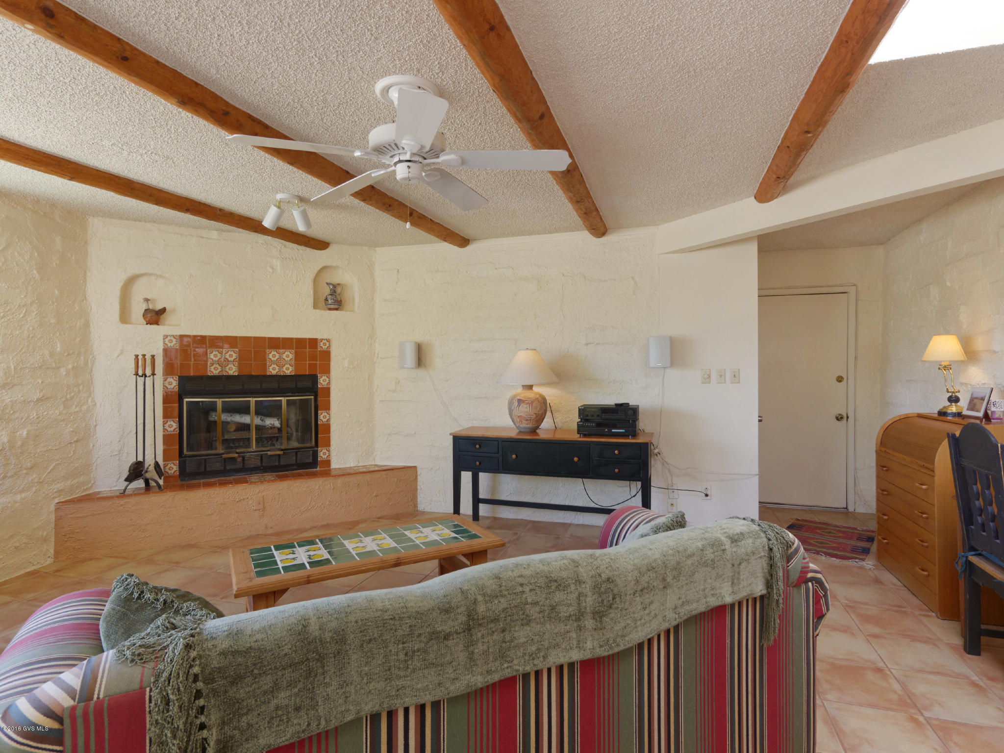 Start the day with coffee in your beautiful courtyard that welcomes you & guests. Inside are maple kitchen cabinets, Saltillo tile, ceramic tile floors, Anderson wooden sliding doors, plantation shutters & remote operated shades. Kitchen has corian countertops & tiled pass-thru opening to the living room. Wooden beams add charm to the family room with an inviting fireplace & mtn. view. Bathrooms have been tastefully updated using modern designed tiles and curb-less shower. Security doors & outdoor lighting with Epoxy paint on garage floors. End unit near community walking path. New roof coating 2016. No GVR and furnished.
