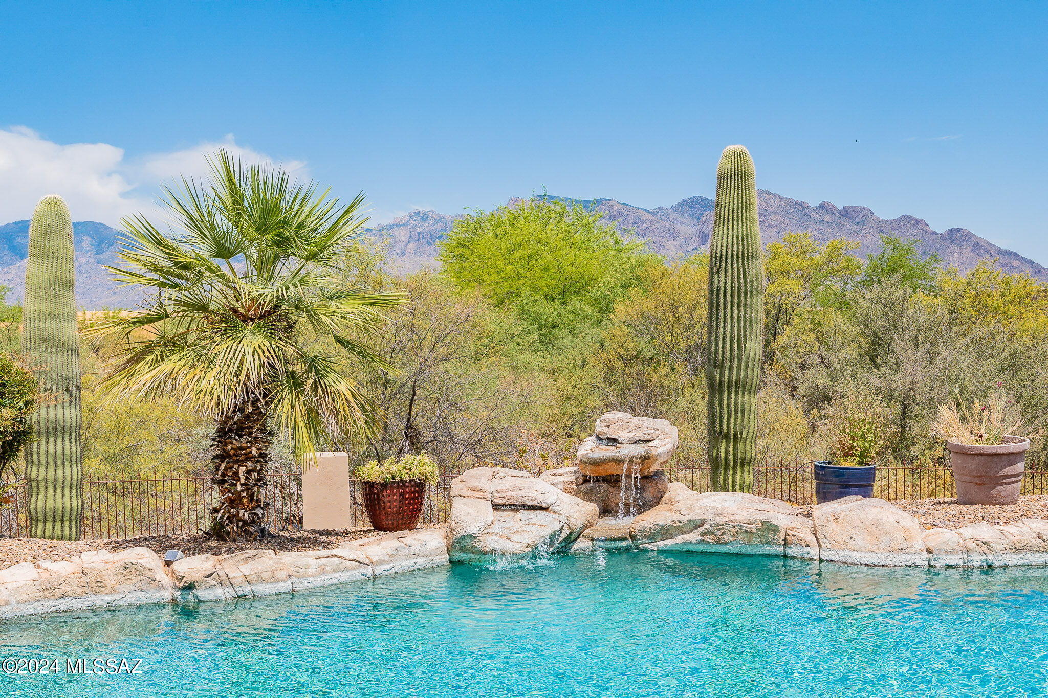 Former TJ Bednar model! SW design w/views of Catalina Mtns & city! Viga beamed ceilings, solid Alder doors, various lighted niches, Kitchen island/breakfast bar, double ovens, 42'' Alder cabinets, wine rack, desk & nook. Family Room and Living Room have Beehive fireplaces! Ceiling fans throughout. East facing backyard with pool (solar heated), spa and water feature. 11' garage ceiling, water softener loop, cabinets in 3rd bay. Laundry cabinets, counter/sink & skylight! Totally owned solar is bonus for Buyer! This home includes back lot for privacy.