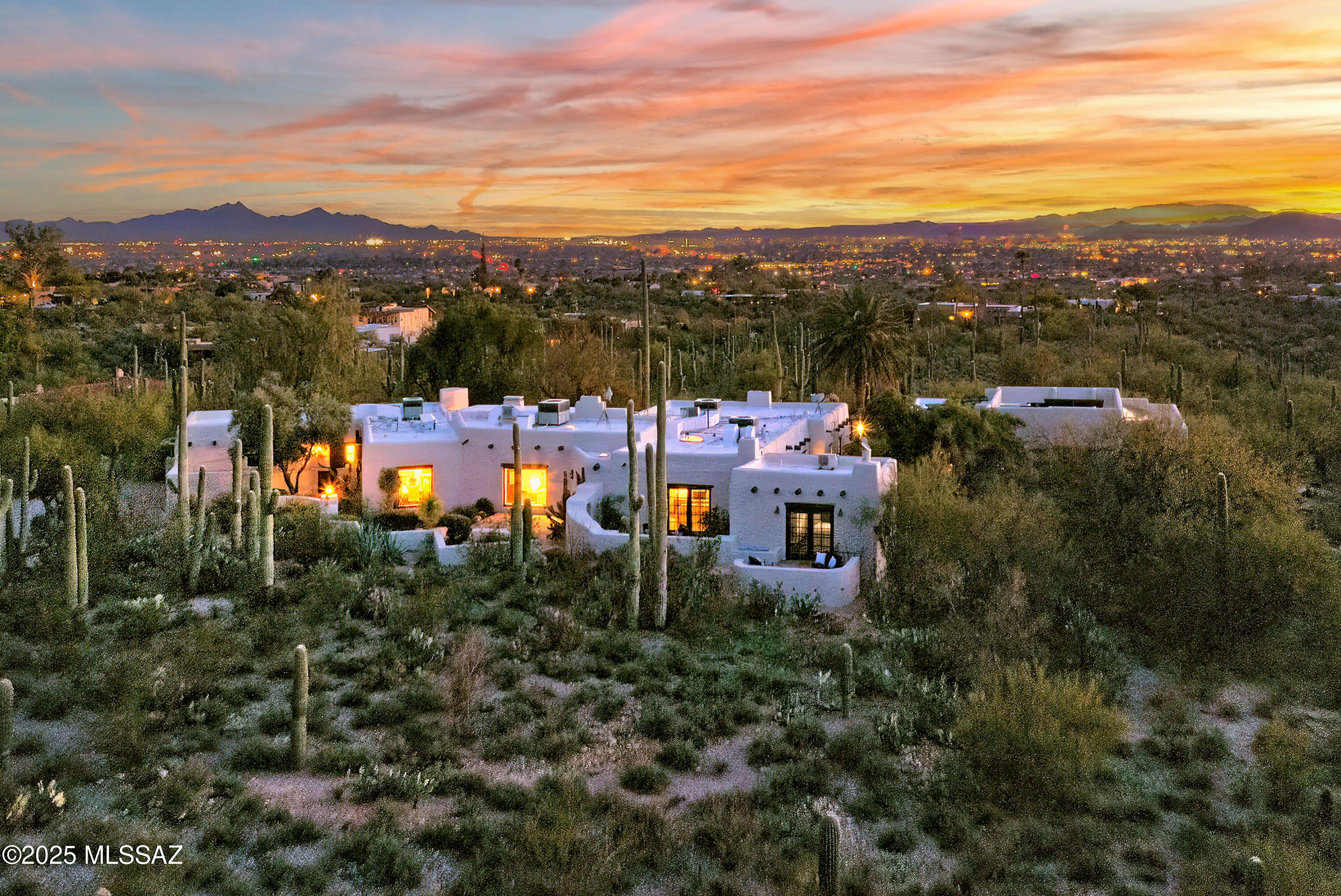 Nestled on an incredible 8-acre hilltop in the Catalina Foothills this stunning 1936 adobe home showcases the timeless beauty of Josiah Joesler's Santa Fe design enhanced with modern updates. Featuring 7 bds and 8 baths the home boasts a brand new roof and 
 newly expanded flagstone entry path. Inside, enjoy the warmth of 5 fireplaces, rough-sawn wood beams, hand-forged metal details, all complemented by restored concrete floors and authentic Mexican tile accents. Oversized windows frame panoramic views of the Catalina, Rincon, & Santa Rita mountains, creating a seamless connection to the surrounding pristine acreage. This exquisite blend of history, luxury, & nature also enjoys a stunning living room w/grand fireplace, formal dining with dramatic iron chandelier & original (SEE MORE) handcrafted sconces, wonderfully remodeled kitchen that honors the original architecture while perfectly blended with modern amenities including a rich walnut butcher block island, stainless steel appliances, soapstone countertops, & breakfast bar seating as well as an eat-in casual dining area. The family room  is a classic Arizona room  with walls of glass windows and French doors that offer sweeping views of the cityscape and mountains beyond. In addition to the main house, a separate guest quarter with a private entrance and mountain-view patio, plus an additional  2-bedroom/2-bath separate guest house with full kitchen, living room, and private city view spa. Outdoors, enjoy courtyards,  2 more fireplaces on patios, built-in BBQ, shady ramadas, a PebbleTec pool with electric pool cover, spa, owned solar panels, and a converted horse stable workshop. With its perfect blend of old-world charm and modern luxury, this property is a true desert sanctuary.