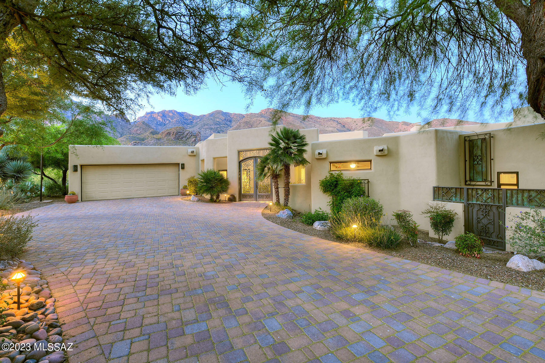Alta Vista at its finest! This beautiful 4785 sq ft, 6 bedroom, 4 bathroom, southwestern home has had an extensive renovation/restoration. Beginning with the multi colored brick circular driveway, custom wrought iron gated entry to a beautiful courtyard with tumbled Travertine, fountain, gardens & authentic bronze sculptures that are visually appealing & welcoming. Moving inside, the custom Alder cabinetry, doors, hand wrought hardware Pella & Sierra Pacific windows throughout are great for energy efficiency & sound insulation throughout the main floor. The well appointed, Cook's kitchen has been updated with Alder Cabinetry, ample storage & top-of-the line appliances, including KitchenAid refrigerator, dishwasher, wine fridge & Thermador double oven, 5-burner stove. Antique Onyx granite countertops & a spacious eat in area overlooking the front garden courtyard. The kitchen is open to the den and offers a built in entertainment center, custom antique onyx granite fireplace hearth, mesquite mantle & custom tiled horse motif imported from Iraq is a stunning feature that adds warmth and character. Adjacent is an office that could be used as a 6th bedroom as it offers an ensuite bathroom.
The living room is impressive with its custom antique onyx granite illuminated steps and tiled corner gas log fireplace, large windows with stunning views of the Santa Catalina Mt's, custom onyx granite-wrapped pillars and metal horse sculpture add visual interest.
The family room is striking with its custom mesquite wood, copper-clad inlays, hot/cold wet bar with fridge, ice maker, and freezer, the stone horse on the custom tiled gas log fireplace, wood floors that adds to the charm and includes a curved screen TV, surround sound and views from every window are also great qualities to enjoy while living and entertaining.
The main floor includes beautifully updated bathrooms, with stone, tile, Alder cabinetry, new light fixtures, glass shower enclosures & are beautifully designed. The main floor primary bedroom is luxurious with its diagonal set, wood, hard-scraped floors and built-in entertainment center, fireplace and luxurious ensuite bathroom with custom tiled floors, his and hers closets, double vessel sinks, walk-in shower with tiled shower surrounds, bench, niches, and double shower heads, private leu and custom-tiled skylights are also great features. Split, second and third bedrooms on the main floor share a private full bathroom.
The fourth and fifth bedroom wing downstairs is very private and has its own entryway to the resort like backyard, desert oasis includes concrete overlay slate designed hardscape, Pebble Tech pool with waterfall & spa, terraced garden planters & unique desert plantings. There is also a separate pool house built-in BBQ under a north facing covered patio with Mt & city light views & is always shaded. Beautifully site on over an acre, plus a 3 car garage with tons of storage. This wonderful property has undergone some amazing updates and renovations, with attention to details and aesthetics making it a luxurious and inviting space to call home. Featured on Dream TV!