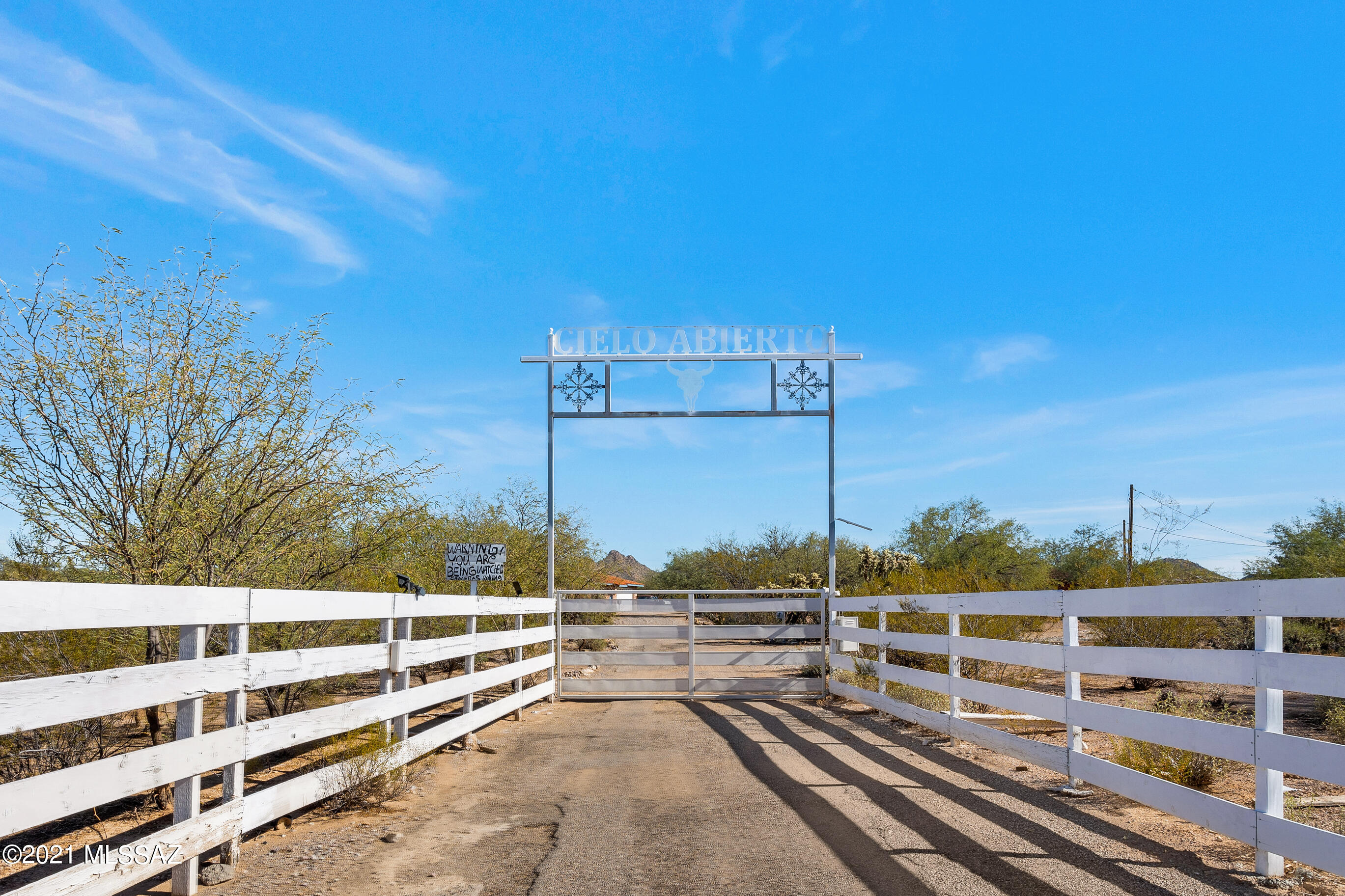 An awesome ranchette with sunset views on 5 acres of usable land.  Yard features corrals, large tack room, hot walker. washing rack, Ramada, & a water feature. Main house has 4 bdr, 3 baths & a gourmet kitchen with Granite counter-tops with chisel edges to add to the rustic ambiance. Home has a  a conversation pit that houses  a  beautiful fireplace, den with a wet bar that includes a wine cooler & sink, semi-formal dining, living room & an AZ room with a pass through window to the kitchen. The 4th bdr has private entrance with bathroom & laundry. Master bedroom features French doors to the covered patio & yard. Master bath has 2 sinks, shower, jetted tub & enclosed toilet room. Separate guest house is situated between 2 - 2-car garages. One can garage 6 cars making this ideal for the car enthusiast and excellent for someone who loves horses.  Guest house has a Full kitchen with 2 bedrooms and one bath.  The land can be subdivided to separate the guest house and main house.  Guest house can be enlarged into garage to create another home.  Yard has a built-in BBQ & trails.  items on property do not convey.  Sign over gate Cielo Abeito does not convey.  Security camera does not convey.