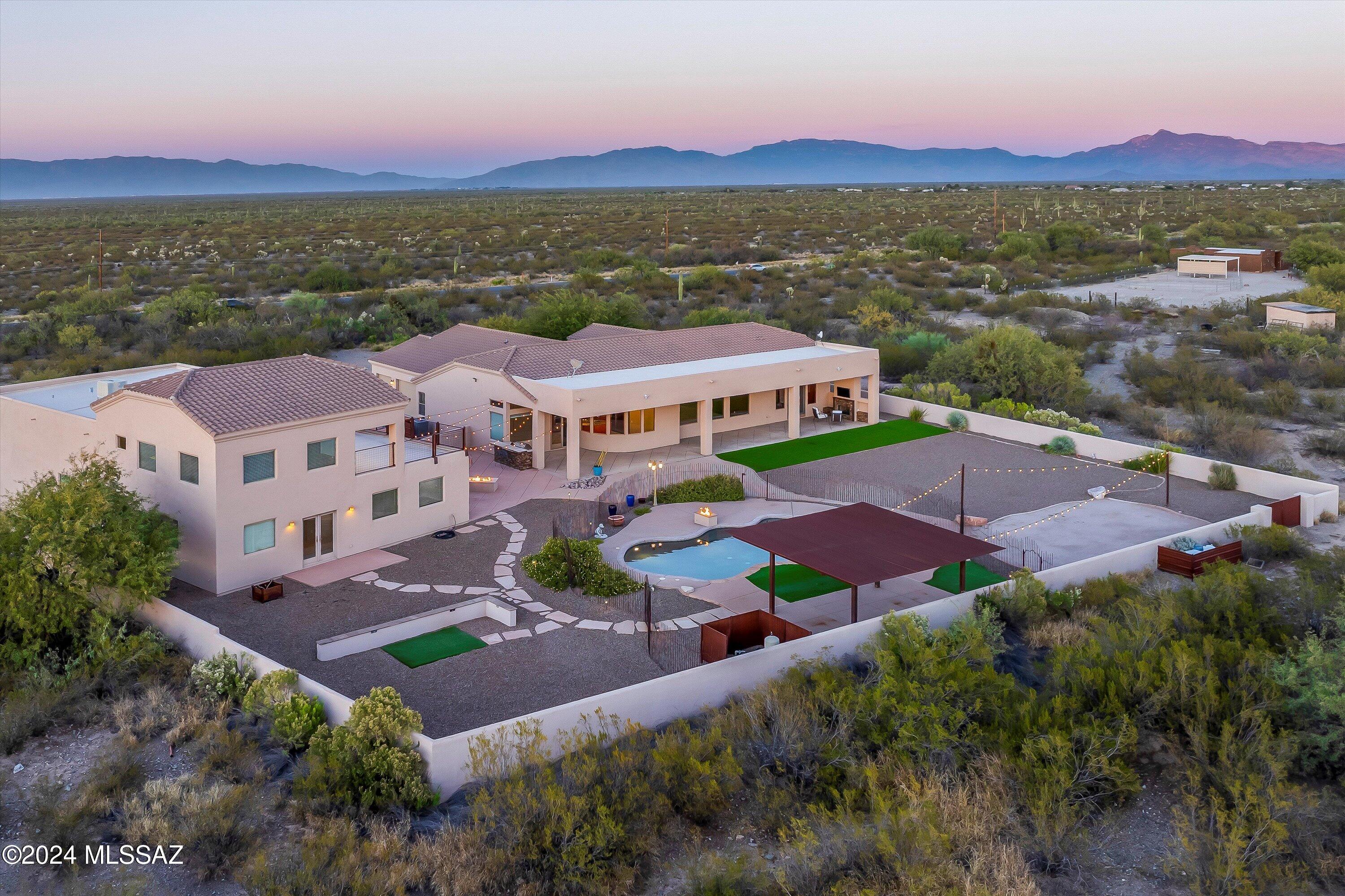 Welcome to your dream home, a 4,300 sq. ft. desert retreat designed for luxury, comfort, and endless possibilities. Set on a sprawling 5-acre property, this home offers breathtaking mountain views, abundant space, and a peaceful escape from the hustle and bustle of city life. With ample land, the property can also accommodate horses, adding even more versatility to its many features.
The main house features soaring 12-ft ceilings and oversized windows that flood the space with natural light and frame stunning views of the mountains and the expansive backyard. A gourmet kitchen with ample counter space flows seamlessly into a large family room and connected dining area, creating the perfect setting for entertaining and family gatherings. The bedrooms are generously sized, with walk-i Welcome to your dream home, a 4,300 sq. ft. desert retreat designed for luxury, comfort, and endless possibilities. Set on a sprawling 5-acre property, this home offers breathtaking mountain views, abundant space, and a peaceful escape from the hustle and bustle of city life. With ample land, the property can also accommodate horses, adding even more versatility to its many features.
The main house features soaring 12-ft ceilings and oversized windows that flood the space with natural light and frame stunning views of the mountains and the expansive backyard. A gourmet kitchen with ample counter space flows seamlessly into a large family room and connected dining area, creating the perfect setting for entertaining and family gatherings. The bedrooms are generously sized, with walk-in closets and modern showers, and one Jack-and-Jill bathroom is ideal for kids to share.
Step outside to your backyard oasis, where you'll find incredible mountain views as the backdrop to your private retreat. The backyard includes a sparkling pool, multiple fireplaces, a ramada for shaded relaxation, a lush grass area, and room for a trampoline. There's also a dedicated space for a hot tub, complete with a TV setup for the ultimate outdoor entertainment experience.
The 2-story guest house is a standout feature, offering a full kitchen and plenty of open space for recreational activities such as arcade games, a pool table, or even a home gym. Attached to the guest house is a massive garage with impressive 13-ft ceilings and a full electric hookup that supports both an RV and an EV charger. The garage can accommodate an RV and up to 4 cars or double as a spacious workshop or creative workspace.
Located in the award-winning Vail School District, known for its exceptional education and community, this property is the perfect blend of privacy, luxury, and convenience. Immerse yourself in the beauty of Arizona nature with the soothing sounds of the desert and scenic views of the surrounding mountains, all while being close enough to essentials for daily living.
Whether you're seeking a tranquil retreat, a space for entertaining, or the option to use the property for horses, this home offers it all. Truly one-of-a-kind, it blends luxury, functionality, and serene living in the heart of the desert.