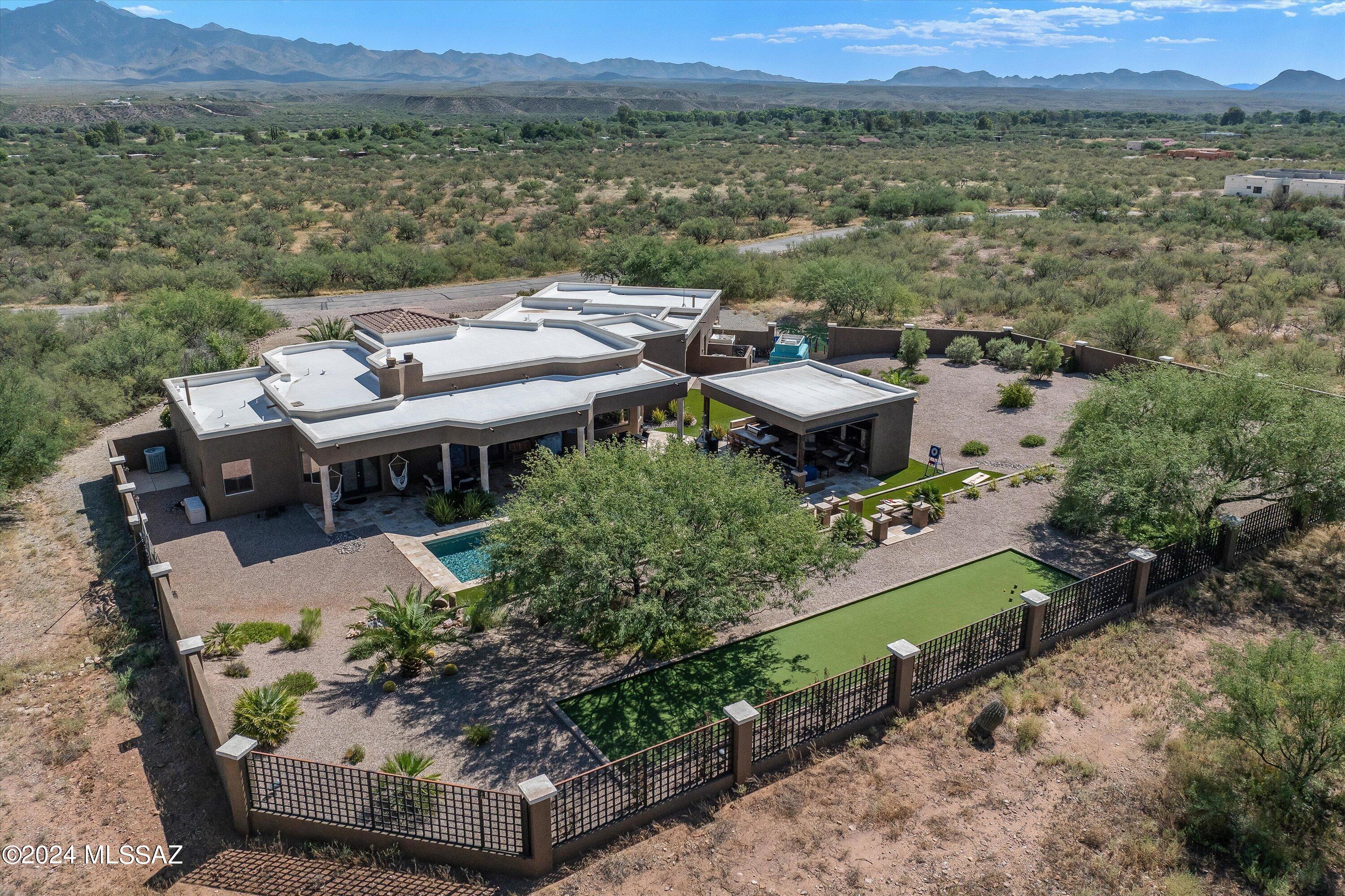 This expansive and luxurious 4-bedroom, 3.5-bathroom estate offers over 4 acres of serene desert living in a gated community. The home features a bonus room off the kitchen and great room, ideal for a billiards room, home office, or formal dining space. The outdoor oasis is perfect for entertaining, complete with a sound system, outdoor kitchen, and plenty of room to host guests. The property boasts a 3-car garage, RV/boat staging area, and ample space for other recreational vehicles in the rear side yard with double gates.
The freshly painted Mediterranean-style exterior welcomes you with a travertine walkway leading to grand 10' double front doors. Inside, an open-concept kitchen and great room are enhanced by stunning natural stone pillars and a wall of windows showcasing... breathtaking views of the Tumacacori Mountains. The newly renovated kitchen is a chef's dream, featuring stainless steel appliances, a large island, an induction cooktop, a Sub-Zero fridge/freezer, a massive walk-in pantry, and a wet bar. The indoor living area is centered around a cozy wood-burning fireplace, which leads out to the rear terrace and private pool for year-round relaxation and enjoyment. This home perfectly blends indoor luxury and outdoor adventure. This backyard will surely impress and is the envy of the neighborhood! The outdoor kitchen features a gas grill, flat-top grill, ice maker, and mini fridge along with a gas fireplace & outdoor TV in the lounge area. The sparkling resort-like pool is surrounded by travertine pavers and artificial turf, elevated levels of gardens, a water feature, and adequate spaces to lounge or play yard activities including Bocce Ball, Corn Hole court, and Darts. The 4-acre lot provides adequate entertaining space indoors and out, with room to expand should you so choose.