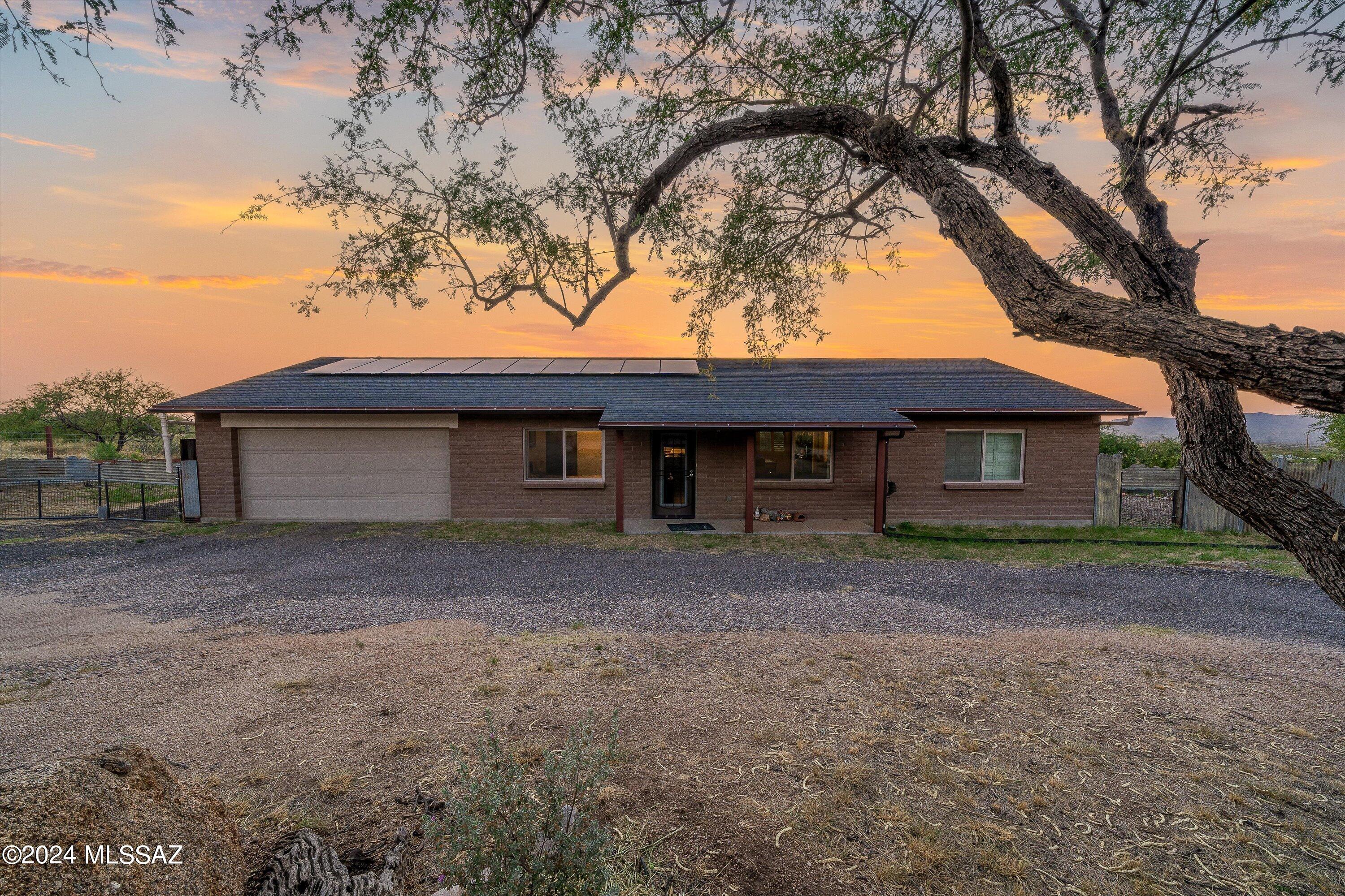 Enjoy a beautiful sunset every evening from this fenced-in 1.25 acre horse property with artistic, sustainable touches. This recently constructed Soule-built home has a split bedroom floorplan, with handicap accessible 3-foot doorways and showers in both bathrooms. The attached two-car garage has a Tesla solar battery, solar panels, and toolbench w/ sink. The expansive yard is ready to be your Oracle homestead, with a separate 120sqft casita with shower/toilet, over 4000 gallons of rainwater catchment tanks, over 18 different fruit/citrus trees, a conex storage container w/ shelves & power, along with structures/shades for livestock & a camper. The large covered porch features a firepit and benchswing - the perfect space for watching the variety of wildlife and incredible panoramic views.