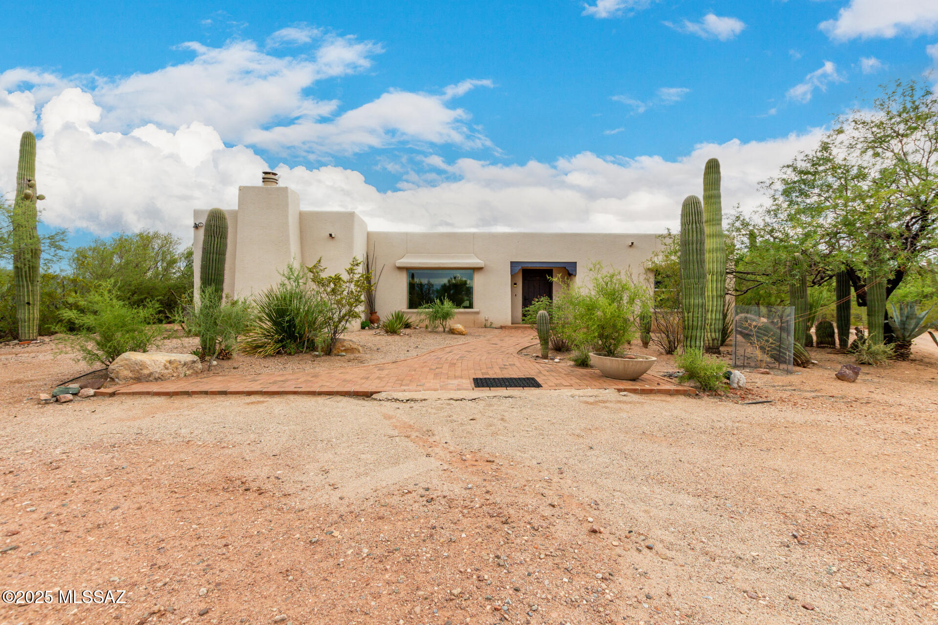 MOUNTAIN VIEWS! This fabulous single-level home is nestled among mature, healthy saguaros. The private 4.77-acre lot backs up to the famous Twin Hill near Saguaro National Monument East hiking trails.

Mid-century enthusiasts will appreciate the pre-wired surround sound system, exposed ceiling beams, and the central atrium bathed in natural light with a cozy atomic fireplace. 

The large open living room takes advantage of the serene mountain views. The kitchen offers plenty of cabinet space, built-in appliances, tile backsplash, and a breakfast bar. Continue to the serene main bedroom offering a beehive fireplace, and a large private en-suite bathroom with dual sinks and a large walk-in closet.

Additional highlights include a flexible den with built-in shelves, a guest bedroom with an adjacent bathroom, and another half bath.A lovely casita with its own enclosed garage separate from the main house sits nearby. Ideal for Air B&B or rental or mother-in-law suite!!Host fun gatherings on the outdoor terrace, lounge in the covered central atrium with the atomic fireplace, or relax in the screened-in patio overlooking the wildlife watering hole. This gem is one of kind built by the original owners.