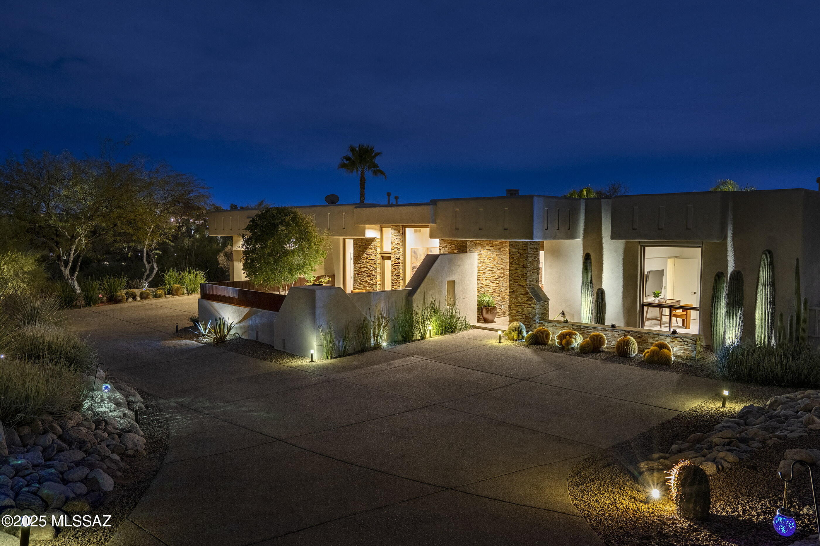 This 3,685 square-foot David Tyson custom residence, situated within the highly desirable guard-gated community of Catalina Foothills 10 and set on 2.19 acres, is strategically oriented to maximize both city and mountain views. The approach sequence is defined by a structured front courtyard, where expansive glazing and low-profile masonry walls frame uninterrupted views of the Catalina Mountains. The envelope is a restrained composition of stucco and steel accents, allowing the structure to recede into the desert setting while maintaining a strong architectural presence. 
Internally, the spatial organization adheres to a disciplined split-plan configuration, optimizing privacy and circulation. Interior flooring transitions seamlessly throughout the residence, where quintessential Manganese saltillo tile juxtaposed against soft white walls creates a measured interplay of cool and warm tones and textures. The kitchen, centrally located and conceived as a functional anchor to the residence, is fitted with full-height cherry cabinetry contrasted by granite countertops and pro series appliances, ensuring a professional-grade culinary environment while establishing a focal point for social engagement. Adjacent to the kitchen, the great room is defined by a series of rhythmic coffered ceilings, an expansive linear fireplace set within a textural slate tile surround, and floor-to-ceiling North and South facing glass panels that dissolve the boundary between interior and exterior.

The primary suite offers a quiet retreat with floor-to-ceiling glass that extends the experience outward, opening to a curated backyard defined by flagstone hardscape, native desert vegetation, and intimate seating areas. The adjoining en-suite bathroom features granite surfaces juxtaposed against dark millwork with metal accents, while a sculptural freestanding soaking tub serves as the focal point. 

The eastern wing of the house encompasses the secondary bedroom suites, each maintaining an architectural language of quiet sophistication. Circulation corridors are intentionally widened to accommodate curated art niches, emphasizing the home's gallery-like sensibility. The overall program of the residence ensures a hierarchy of spaces, balancing communal engagement with secluded retreats.

Externally, the home's rear elevation is a masterclass in indoor-outdoor integration. Expansive covered terraces extend from the main living areas, offering uninterrupted city views that transform as day transitions to night. The resort-caliber pool and spa are executed with precision, featuring an infinity-edge detail that visually dissolves into the desert landscape. An adjacent outdoor kitchen, is strategically positioned to command panoramic north and east mountain vistas. The result is an architectural statement that is both grounded in its desert context and elevated in its execution - a residence that transcends mere habitation to become an experience of place.