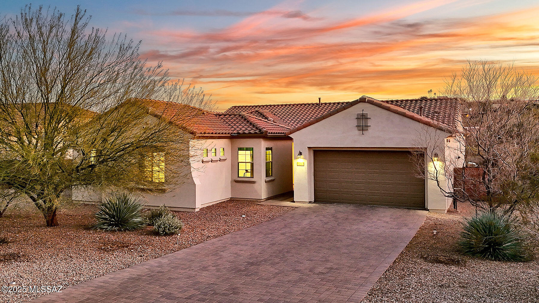 This wonderful semi-custom Pulte home, built in 2018, is a testament to modern design and comfort. Its next-generation layout showcases a grand great room floor plan with soaring 10-foot ceilings, stately 9' doors.  The space seamlessly flows into a formal dining area, a cozy breakfast nook, and an expansive, well-appointed chef's kitchen. Thoughtfully designed with both beauty and functionality in mind, the kitchen features a generous walk-in pantry, a central island with a breakfast bar, stainless steel appliances, a convection oven, and a five-burner gas cooktop.
The heart of the home is further enhanced by a spacious living area adorned with a striking glass gas fireplace and custom built-in niches, perfect for showcasing art or treasured keepsakes. The primary bedroom suite offers a private retreat, complete with an ensuite bathroom, a walk-in closet, and elegant French doors that lead to the backyard. An additional den or bedroom currently serves as a home office, powder room and a second bedroom is conveniently located near a full bathroom.
A unique highlight of this home is the separate two-room suite, accessible through a private entrance. This suite features its own ensuite bathroom and walk-in closet, making it an ideal space for hosting guests, accommodating family, or creating a private retreat.
The outdoor space is equally enchanting, offering breathtaking views of the Rincon and Catalina Mountains. A covered patio and colored concrete pavers provide the perfect setting for outdoor gatherings, relaxation, or simply soaking in the beauty of the desert landscape. The garage, with its four-foot extension, offers ample space for larger vehicles and additional storage, ensuring practicality meets style in every corner of this remarkable home.