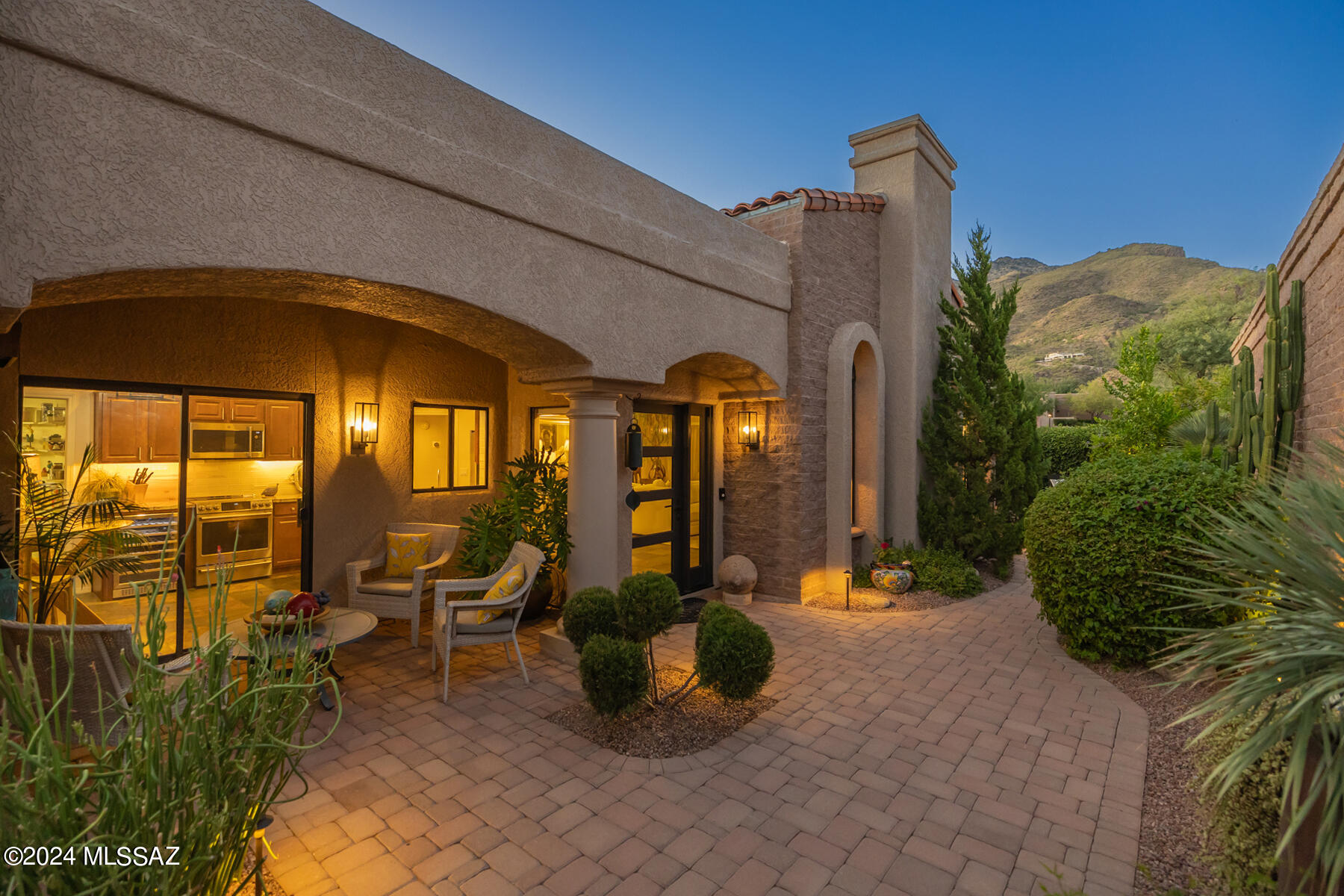 Experience serene desert living in this beautifully updated home nestled within Ventana Serena, behind the main gate of Ventana Canyon. This 1,836 sq. ft. property features 2 bedrooms, 2 baths, and slate flooring throughout. The fully modernized kitchen, baths, and laundry room add a touch of luxury, with the kitchen showcasing a wine cooler, GE Café stainless steel appliances, an induction cooktop, and granite countertops. The great room offers a cozy fireplace, while large windows bathe the home in natural light and frame stunning mountain views from the den. Step into your own secret garden in the backyard—an escape with lush landscaping, a tranquil tall jar fountain, and total privacy. The beautifully designed paver courtyard and vibrant greenery create the perfect retreat for relaxation. This Ventana Canyon home seamlessly blends elegance, comfort, and an intimate outdoor oasis surrounded by breathtaking mountain views.