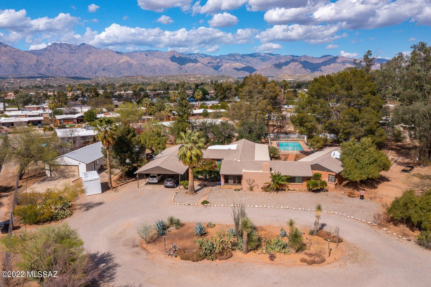 Welcome to a truly one-of-a-kind property in central Tucson--5923 E. Seneca Street. 3,818 square foot main house and 714 square foot guest quarters, courtyard, pool, 6 car detached garage and workshop sit on 1.6 + sprawling acres. Mid-century modern charm everywhere you look (check out the cute bathrooms and fireplace) with modern touches like granite kitchen counters, wet bar, a new roof, new main AC unit (and 2 mini splits in the guest quarters). Main house has 4 bedrooms (one with cedar closet) and 3.5 bathrooms (2 en-suite). Tons of natural light—oversized windows look out to gorgeous pool and backyard from almost all directions. Beautiful mature trees and included adjoining lot guarantee ulta-private living experience while still being exceptionally close to shopping, dining, the Loop Recreational Path and just 1 mile to TMC. Guest house has 1 bedroom, 1 full bath, and living room (excellent rental income opportunity!) This property has endless potential!  Sale includes adjoining lot Tax ID # 121-01-070T.