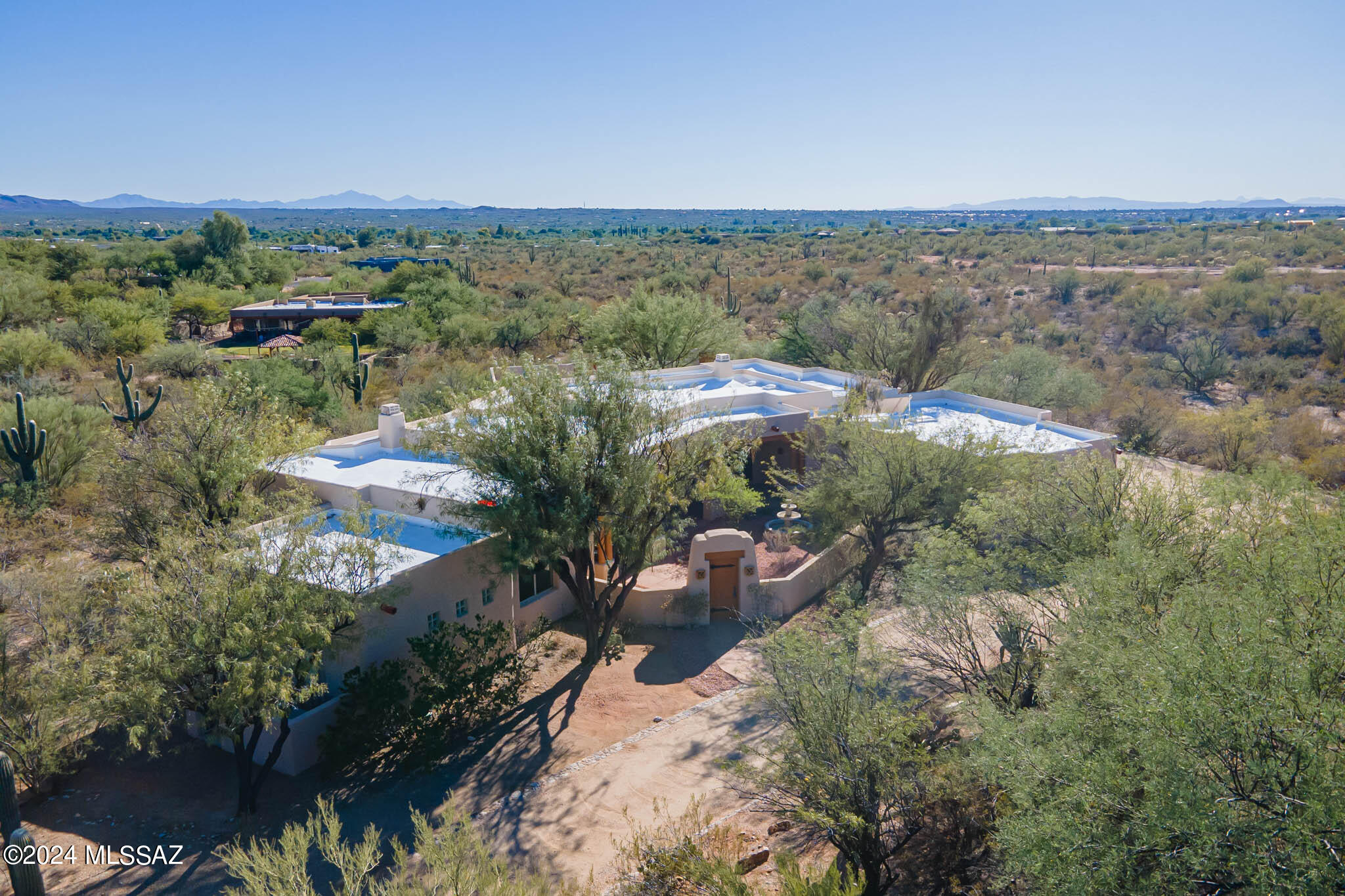 Situated on a commanding view lot enjoying sweeping vistas of both the Catalina and Rincon Mountain Ranges, this stunningly luxurious Santa Fe style home in a lovely upscale North East Side Neighborhood provides tranquility and privacy. Transparent facades and multiple glass doors fuse indoor and outdoor living environments, providing the easy outdoor access that is recognized as part of a healthy lifestyle. Featuring tall ceilings and well-utilized Santa Fe elements of corbels, vigas and lintels and both front and rear ''portales'' or broad covered terraces, richly shaded stone/ceramic flooring and a ''Texas-Size'' spacious floor plan on one level, the design facilitates relaxed easy living. Walls of oversized windows provide never-ending vistas of mountains and desert, along with an abundance of natural light throughout the home. The home provides four bedrooms and 3 baths, with a luxurious Owner's Suite showcasing a beehive fireplace, oversized Jacuzzi tub, walk-in shower and sumptuous closet. Three additional bedrooms provide space for guests, office/library and family. A large laundry room provides more storage and a sink, while the oversized garage has an enclosed storeroom.
 Materials in the home feature carefully selected, easy to maintain choices of rich woods juxtaposed with elegant stone/ceramic surfaces and granite. Enjoy a shaded front courtyard enjoying a broad and deep covered portal (Terrace), Catalina Mountain views and a handsome tinkling fountain. A similar rear portal has multiple gathering spaces and built-in banquettes, with plenty of space beyond for a stunning pool and fruit trees. This welcoming home is immaculate, impeccably clean, recently repaired and updated, and ready to entertain new owners.