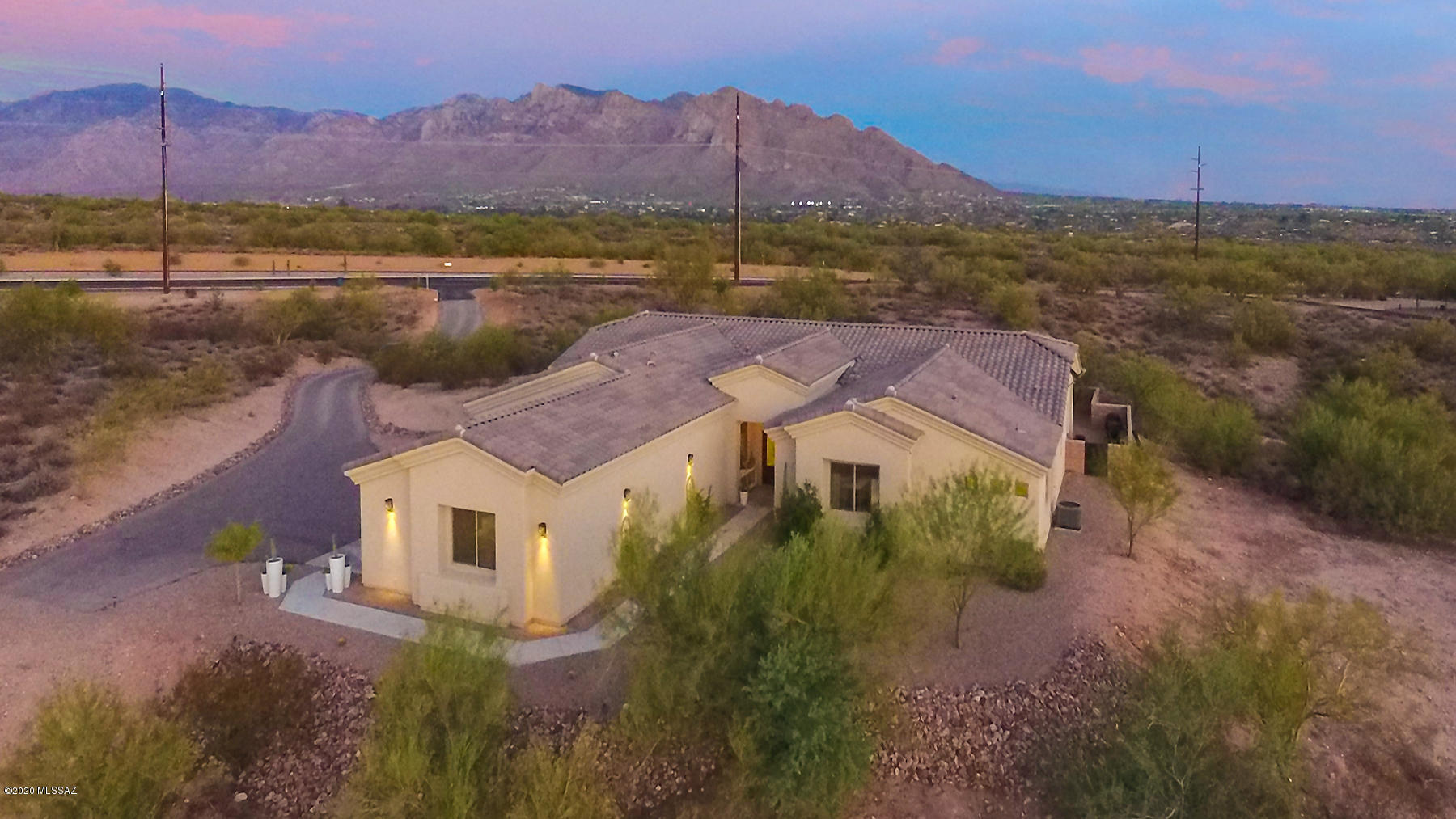 Ext photos in virtual tour! A custom home builders' personal residence – must see to appreciate.  5 bdrms, 3.5 baths, great room open to the kitchen, with living & dining room.  This home is situated on the lot to take ultimate advantage of views of the Catalinas, Mt. Lemmon, and city lights from the main living areas AND the massive master bedroom suite. Panoramic views of the Tucson mountains and Sombrero Peak to the west, too. The upgrades are endless: spray foam insulation, upgraded A/C units, tankless water heater, custom mirrors, huge tiled Master shower, integrated smart home technologies, outdoor shower, heated pool & jacuzzi. Large slider opening to expansive covered patio and firepit - perfect for entertaining! This home has served as a showcase home for potential custom client Note that La Cholla improvements are complete and you can walk/bike to Tangerine Rd north or south to Magee and Ina  catch the loop either way! Incredibly convenient location with setback from La Cholla creating privacy while still maintaining views.