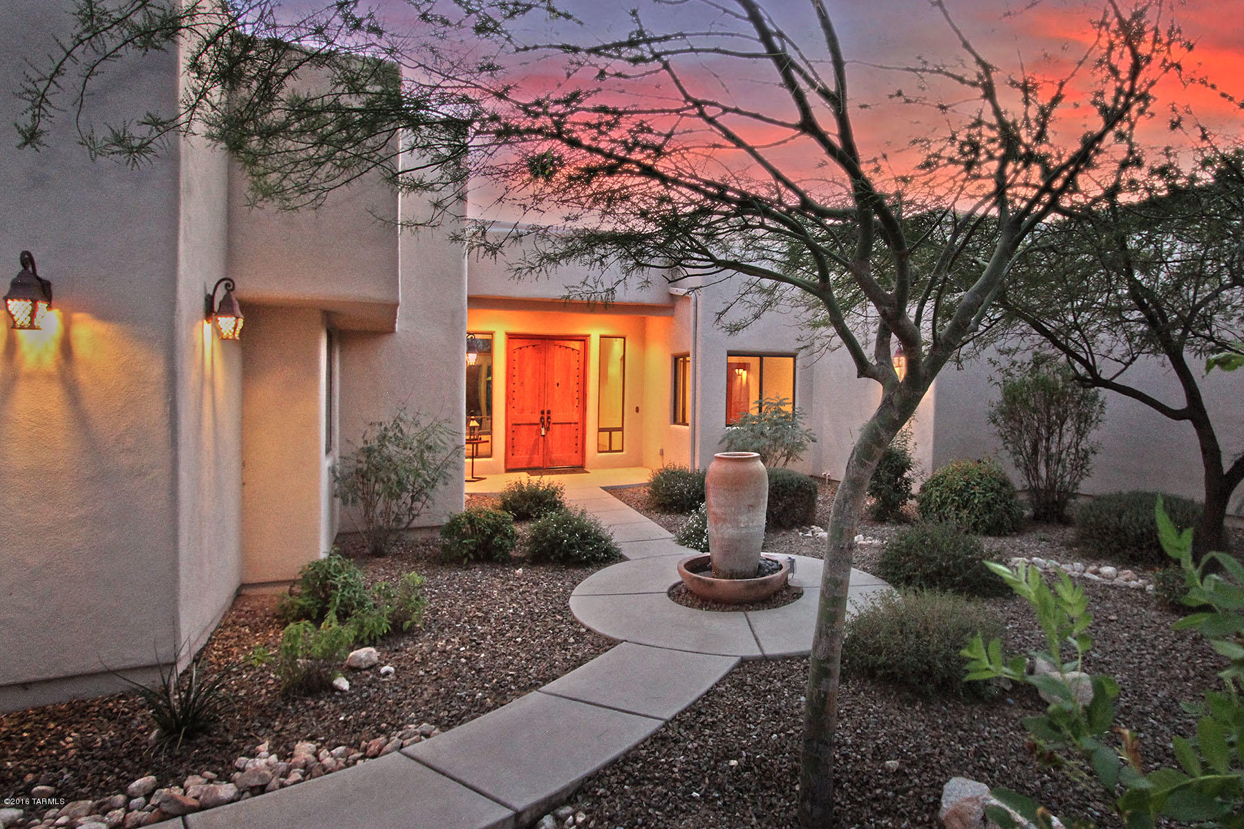 Welcome to a very private, elegantly spacious Southwestern Contemporary home in gated and prestigious La Reserve.  Bucolic and dramatic views from many oversized windows are imbued by graciousness and warmth throughout the home. With warm inviting areas to live, relax, work and entertain, this is a home for the most discriminating buyers.  A beautifully landscaped front area with a large adobe vessel fountain, and heavy authentic mesquite wood double doors with bronze hardware, sets the stage for entry into the foyer with an elegantly understated chandelier set into a recessed ceiling dome. One’s eyes glide over the spacious living area and out the wall of windows to the verdantly green mountainside topped with the boulders at the top of dramatic Pusch Ridge, a landmark of the Oro Valley area. (In the Chinese feng shui system, an upsloping mountain behind a home brings stability and good fortune!) Continue to the gorgeous kitchen, breakfast room with more walls of windows looking up the slope to the peaks of Pusch Ridge, and the commodious family room with banks of tall oval topped windows providing yet more lovely views and flanking a unique "bee hive" fireplace, a fabulous gathering spot for friends and family. The kitchen has counters in a thick, richly shaded golden granite that blends elegantly with the glossy mahogany-finished concrete floors found throughout the home (except bedrooms which are cozily carpeted). A plethora of handsome richly shaded handmade mesquite wood cabinets extend to the ceiling, with leaded glass windows on upper lighted cabinets. A large walk-in pantry extends the bountiful storage found in the home, along with a super-sized side-by-side refrigerator & freezer. The central island, topped with beveled-edge granite, includes a bar sink of hammered copper, a theme continued with an oversized farmhouse main sink and hammered bronze hood above the five-burner cooktop. A curved granite "breakfast bar" seats eight with ease, while the adjacent "breakfast" area overlooks bright bougainvillea and a gorgeous yard with "Arizona grass" and provides more views up the verdant hillside to those Pusch Ridge peaks. The family room, with a curved wall of banquette seating accented with tall windows and flanking a substantial and unique "bee hive" gas fireplace, provides plenty of space to spread out, yet also a cozy feeling.  A sound-proofed media room with all needed connections is adjacent to the family room. The entry from the oversized 3-car garage is into a mud room with lots of storage and a bench to sit down and take off your hiking shoes before entering the main part of the home. A powder room with more granite counters, hammered copper vessel sink and glassed-in shower and an office overlooking the lushly landscaped front yard and adobe vessel fountain complete the "South Wing" of this magnificent home. The "North Wing" provides a "WOW" master bedroom suite with views over the tranquil pool and spa, up the mountainside to those Pusch Ridge peaks, and a wall of art alcoves individually lit with bookshelves below. The spacious master bath features black granite gold-flecked counters perfectly accented with hammered copper sinks and bronze hardware, a large Jacuzzi tub set in an earthy granite tile surround (room to set down that book or glass of Chardonnay!) under yet another large window with "those views", and a beautifully glassed-in shower finished with more earthy granite tiling. Two substantial walk-in closets proved extensive built-in drawer, cabinet and shelf storage. Four additional smaller bedrooms with well-planned walk-in closet storage and two full baths complete the north side of this very special home. Art niches and bookshelves are found throughout the home. The large rear yard provides a broad deep covered terrace overlooking the softly blue-green gently curved pool that blends harmoniously with surrounding green trees and rocky vistas. The pool has a "beach" landing entry. An adjacent spacious circular spa provides deep circular seating with lots of space for relaxing and listening to only the breeze gently rustling nearby trees for accompanying sound. There's a green "turf'" area (putting green, anyone?) and of course "those views", including city lights to the south. This is retreat for the senses both inside and out, with an overall sense of elegant harmony, and an abode for those who appreciate a home that is truly one of the best Tucson has to offer.