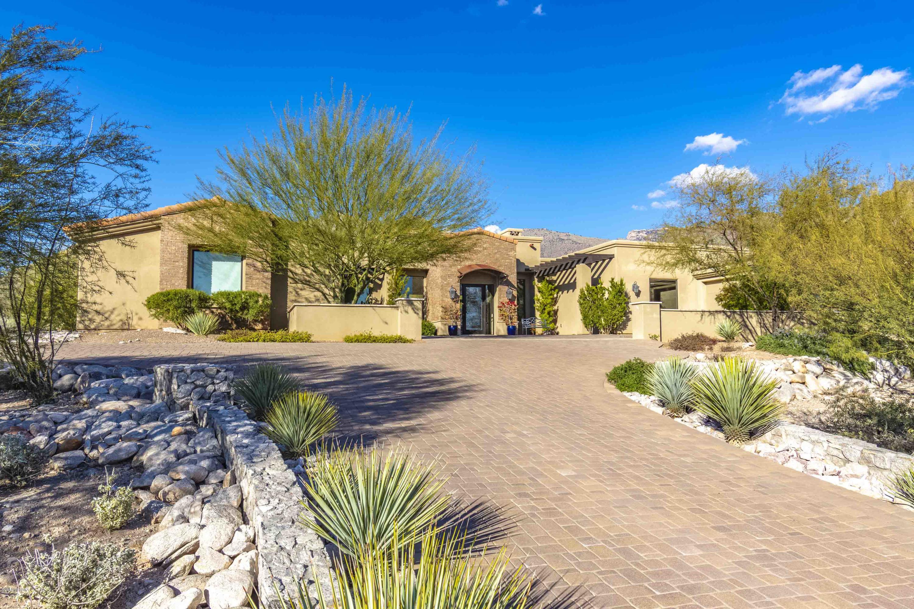 Contemporary home in prestigious, gate Pima Canyon Estates in Tucson's Catalina Foothills with 4 bedroom split plan with ensuite baths plus studio or exercise room.  Fabulous city and mountain views.  Enter through the inviting courtyard with brick pavers that leads to entry into Living Room with high ceilings and windows and lots of light, travertine floors throughout, beamed ceiling and fireplace with cantera stone surrounds.  Walk into the kitchen that offers gourmet kitchen and granite counters, designer SS appliances, alder cabinets and doors, center island that is an entertainers delight, separate breakfast bar and floor to ceiling brick fireplace opens up to the great room.  Come relax in the large master suite that features a garden tub and oversized walk-in closet with built-ins. Enjoy nice evenings on the expansive paver porch overlooking the fully landscaped rear yard.